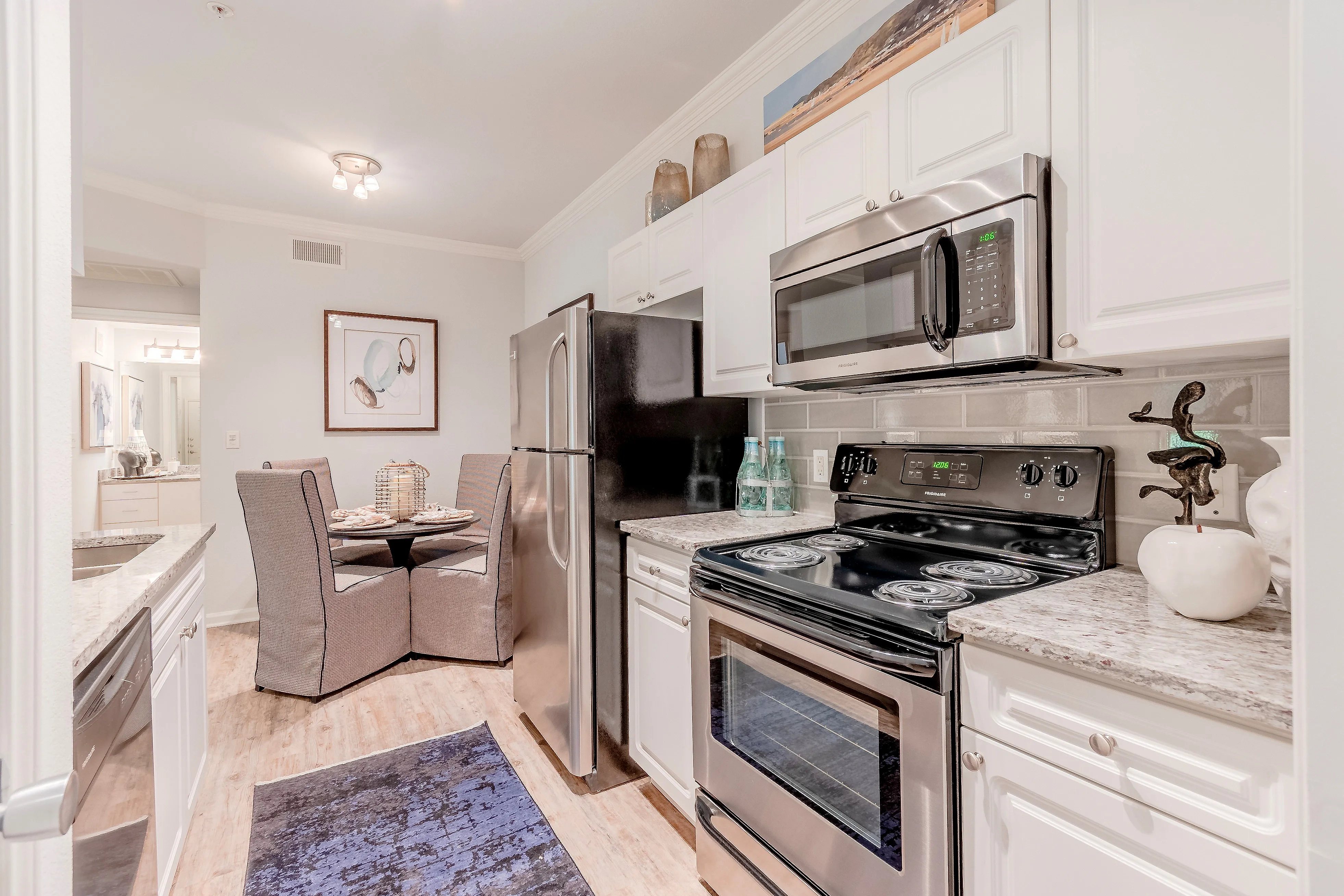 Modern kitchen with sleek stainless steel appliances, elegant dining nook, and stylish decor, highlighting a cozy and inviting atmosphere.