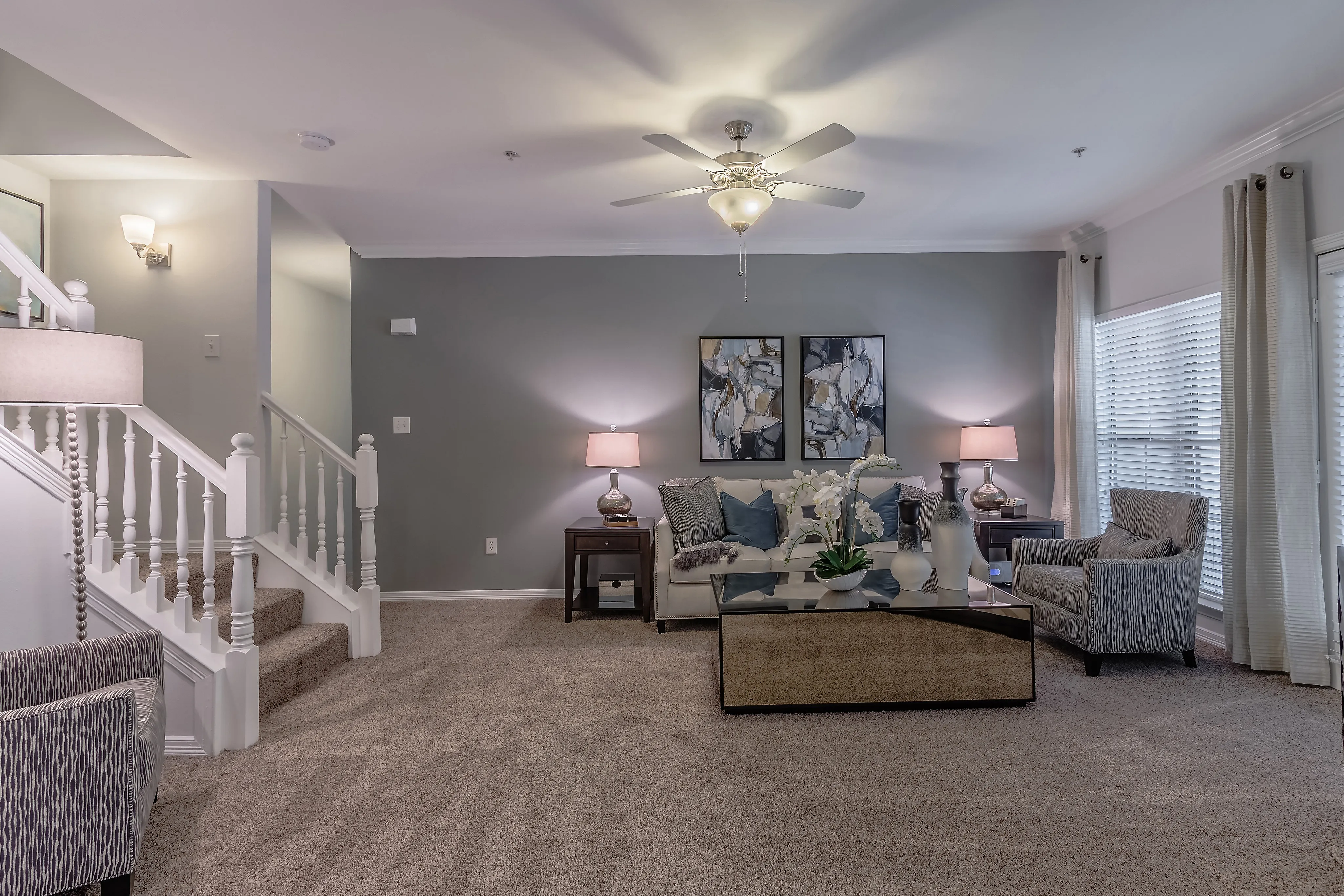 Chic living room with elegant decor, plush carpeting, stylish armchairs, and a modern staircase.