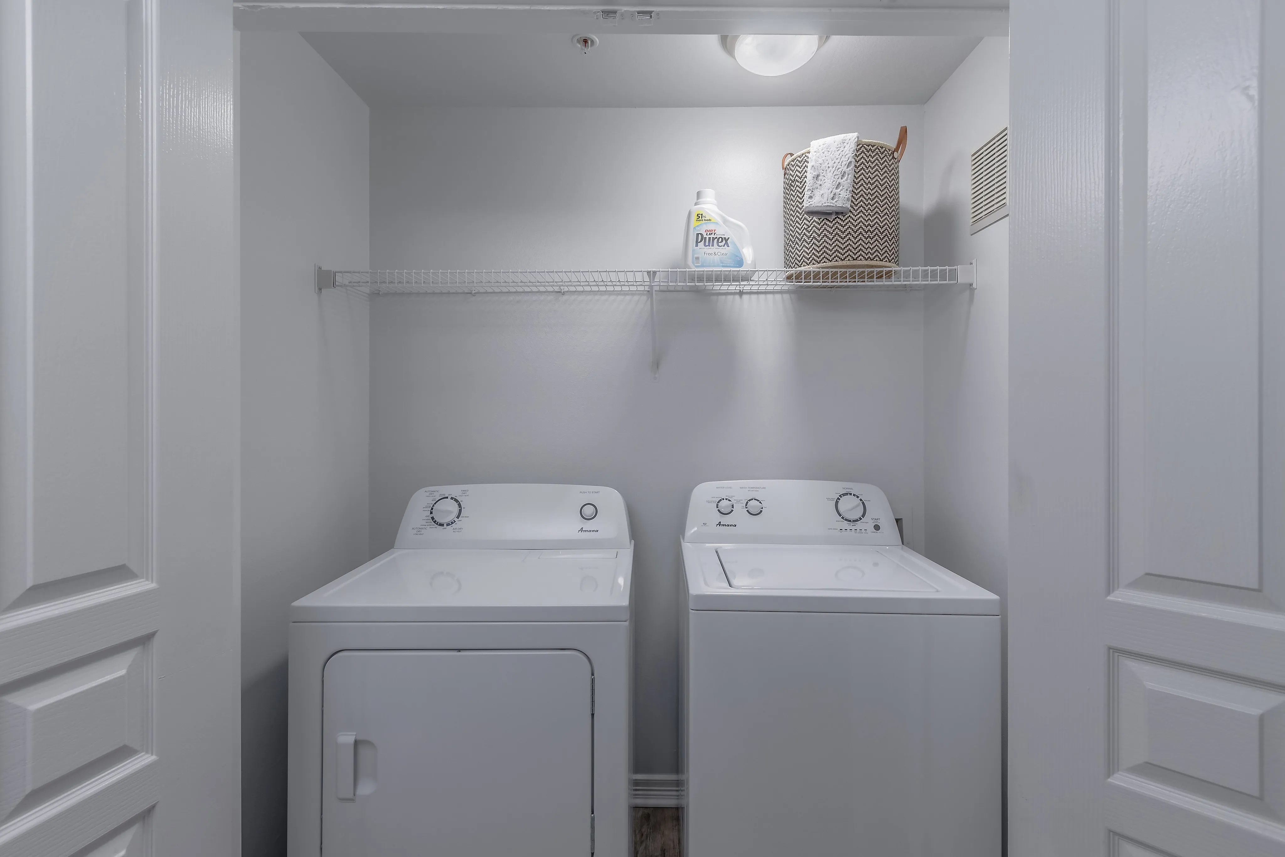 Modern laundry room with sleek white washer and dryer, featuring ample shelf space for storage.