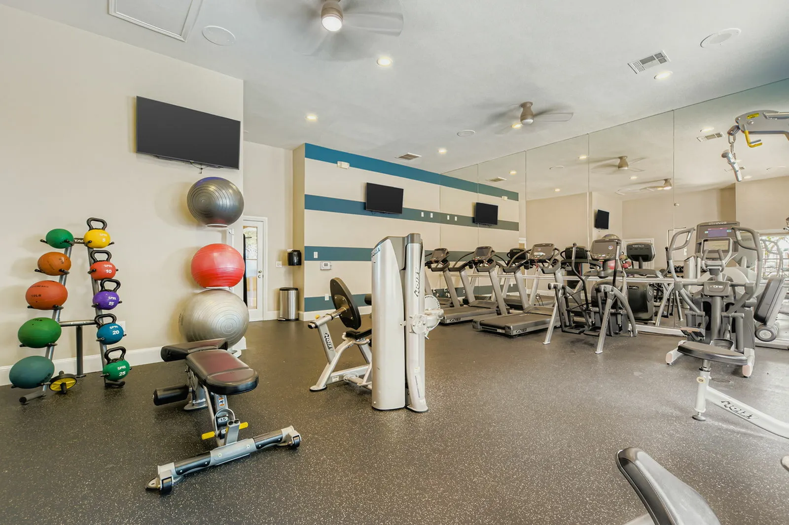 Modern gym facility with state-of-the-art treadmills, strength training equipment, and vibrant exercise balls, promoting a dynamic workout environment.