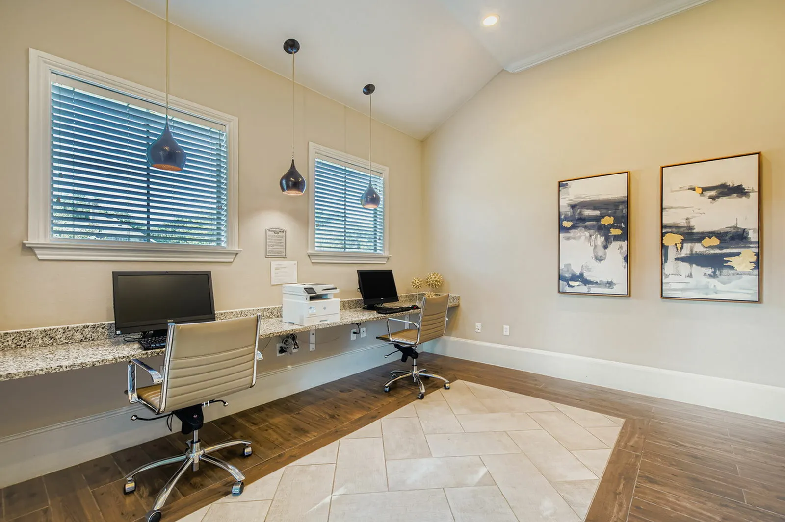 Chic and modern office space with two workstations, sleek pendant lighting, and vibrant abstract artwork.