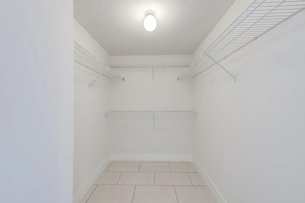 Spacious walk-in closet with modern wire shelving and bright lighting, perfect for organized storage.
