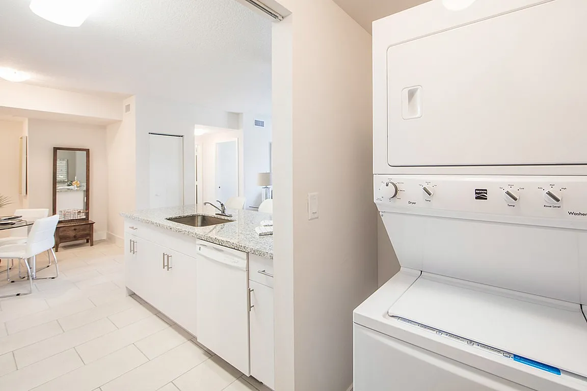 Bright and modern kitchen with granite countertops, integrated laundry appliances, and a welcoming dining area.