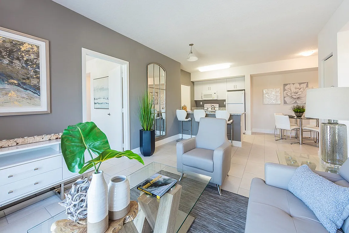 Bright and modern open-concept living room and kitchen with elegant decor, featuring stylish seating, contemporary art, and a cozy dining area.