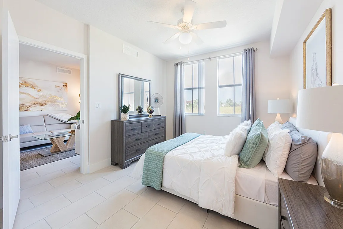 Bright and airy bedroom with modern decor, featuring a comfortable bed, elegant dresser, and large windows providing plenty of natural light.