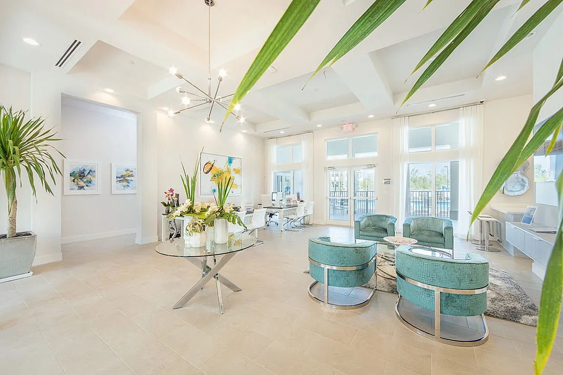 Bright and inviting modern living area with elegant decor, teal seating, and abundant natural light through large windows.