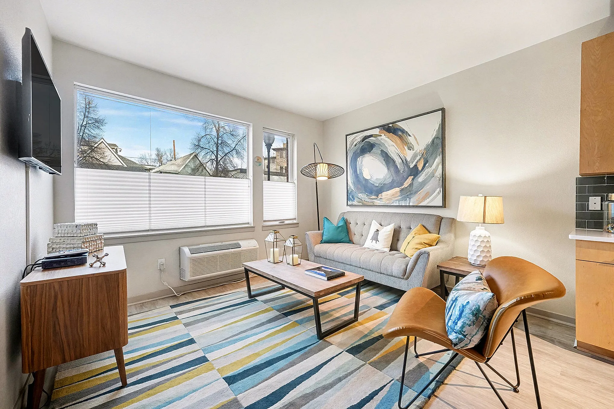 Chic living area with modern decor featuring a cozy sofa, stylish artwork, and an open kitchen with sleek appliances.