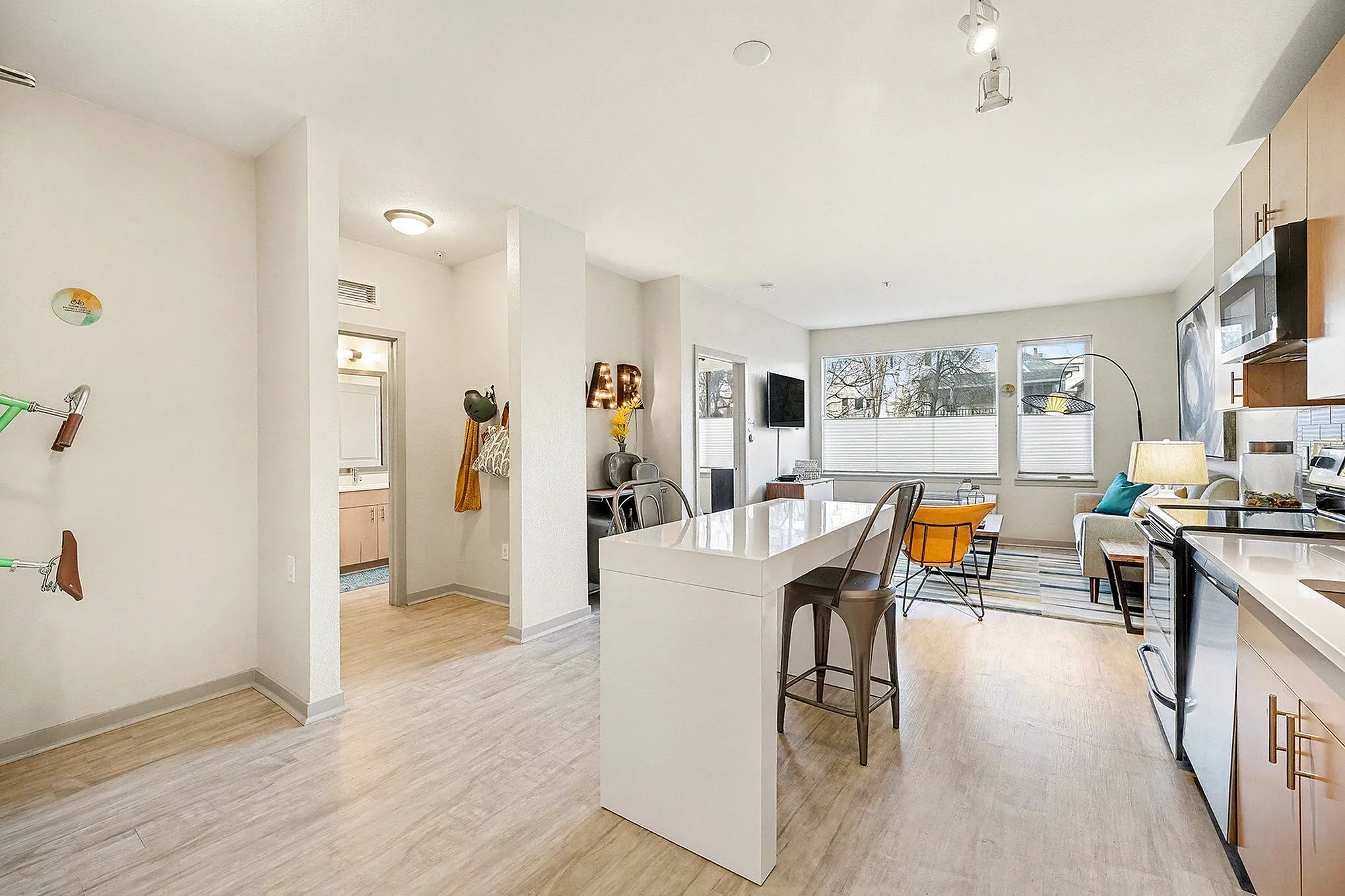 Modern apartment kitchen with sleek cabinetry, island dining, and open living space, featuring abundant natural light and contemporary decor.