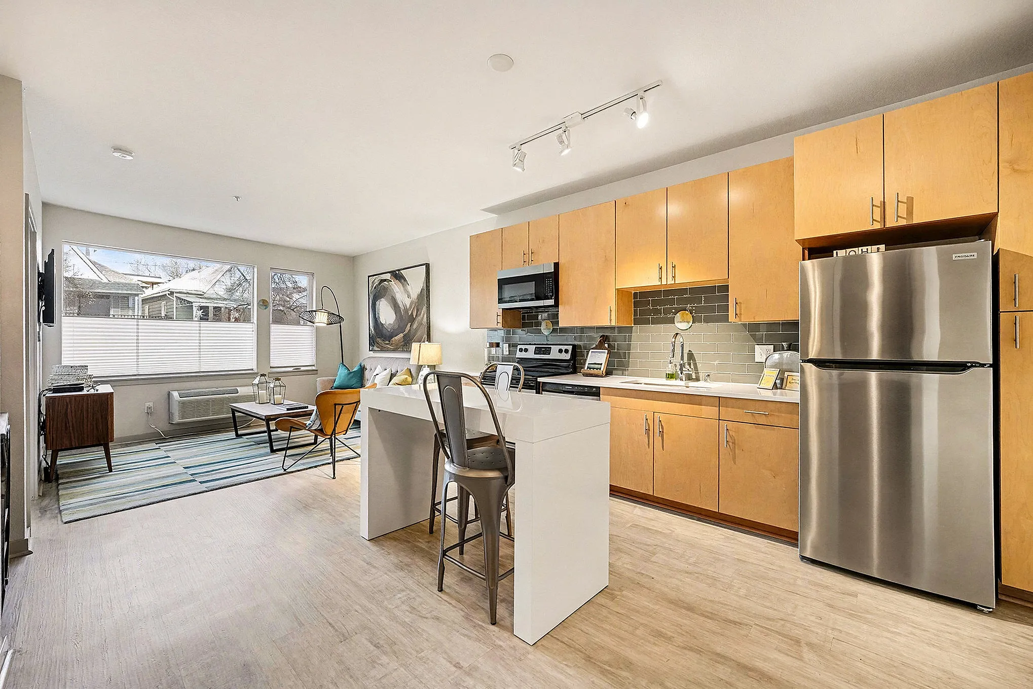 Modern apartment kitchen with sleek cabinetry, stainless steel appliances, and chic lighting. Cozy seating area with stylish decor complements the open layout.