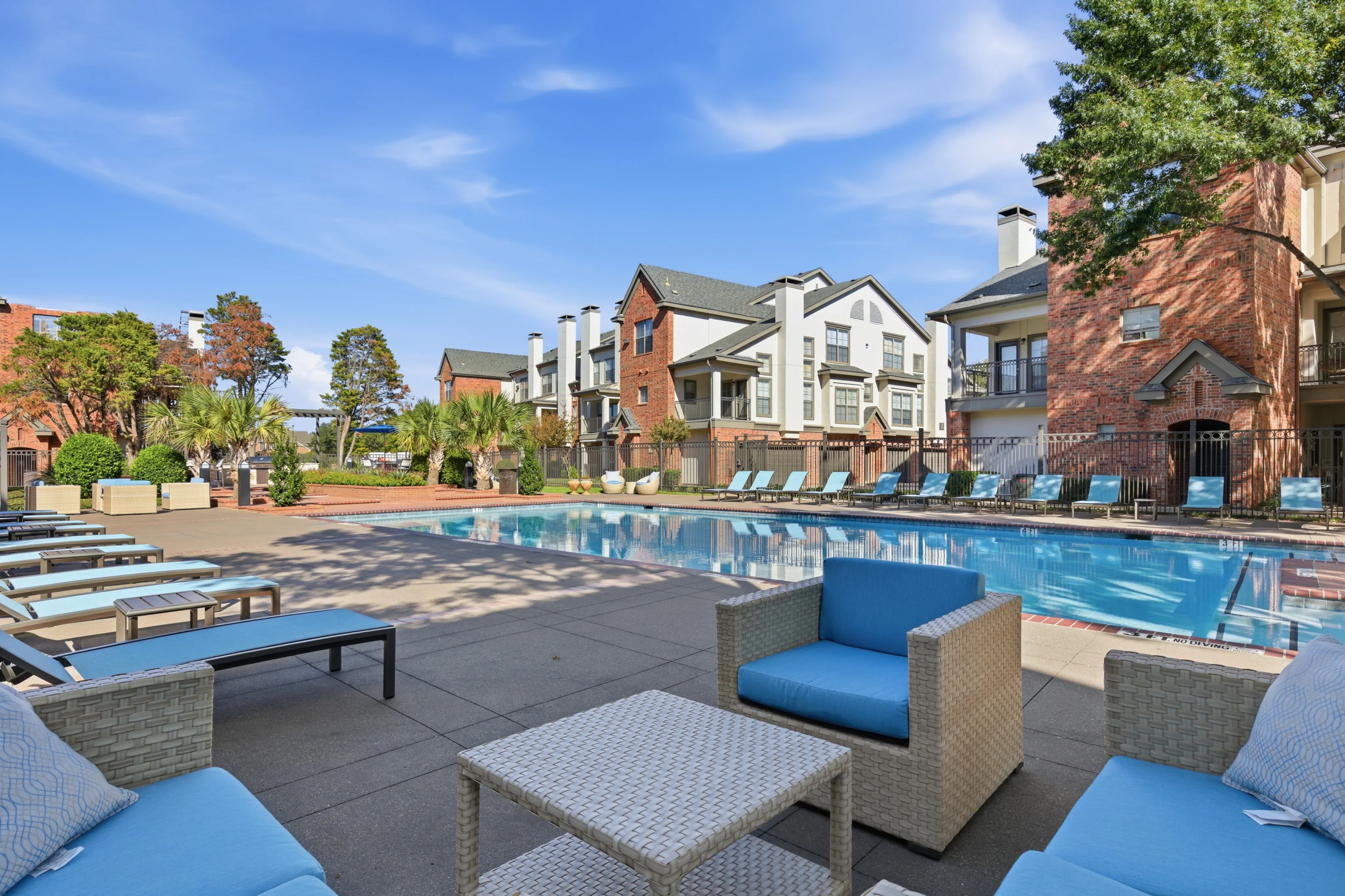 Luxurious apartment community featuring a sparkling pool, tropical landscaping with palm trees, and modern lounge areas for relaxation.