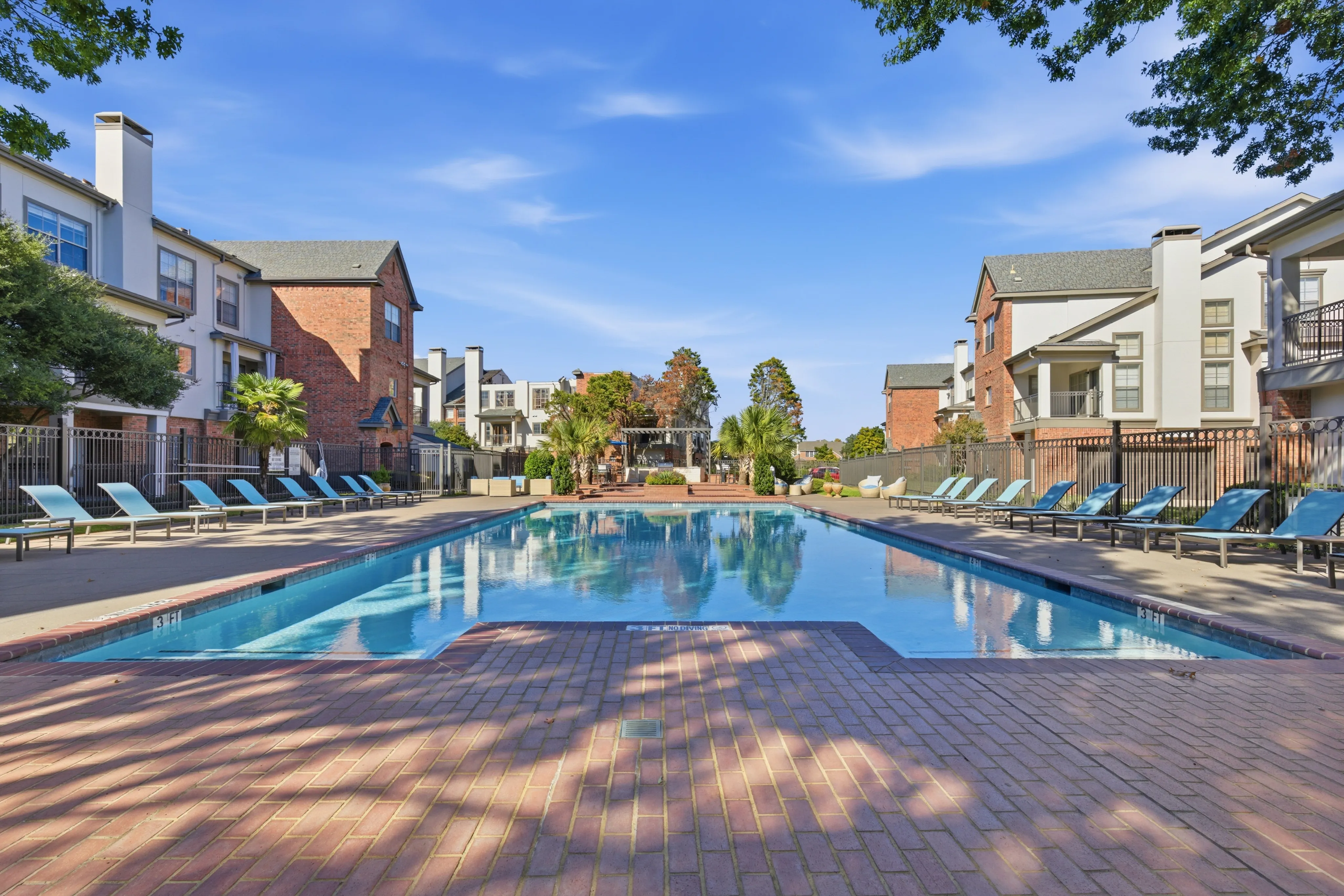 Luxurious apartment complex with a sparkling pool, surrounded by elegant brick architecture.