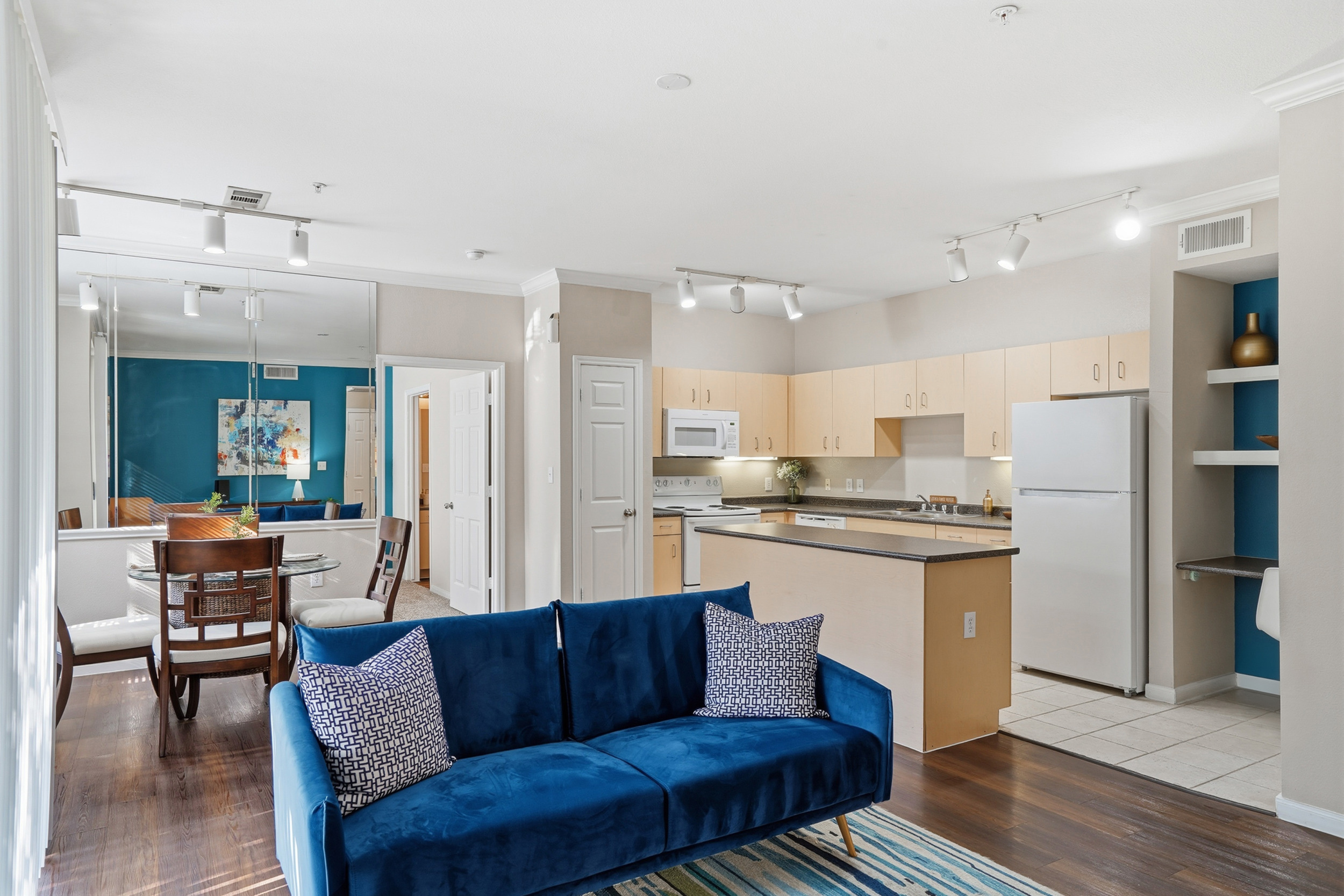 Elegant open-concept living room and kitchen with modern decor, featuring cozy seating, stylish dining area, and sleek hardwood floors.