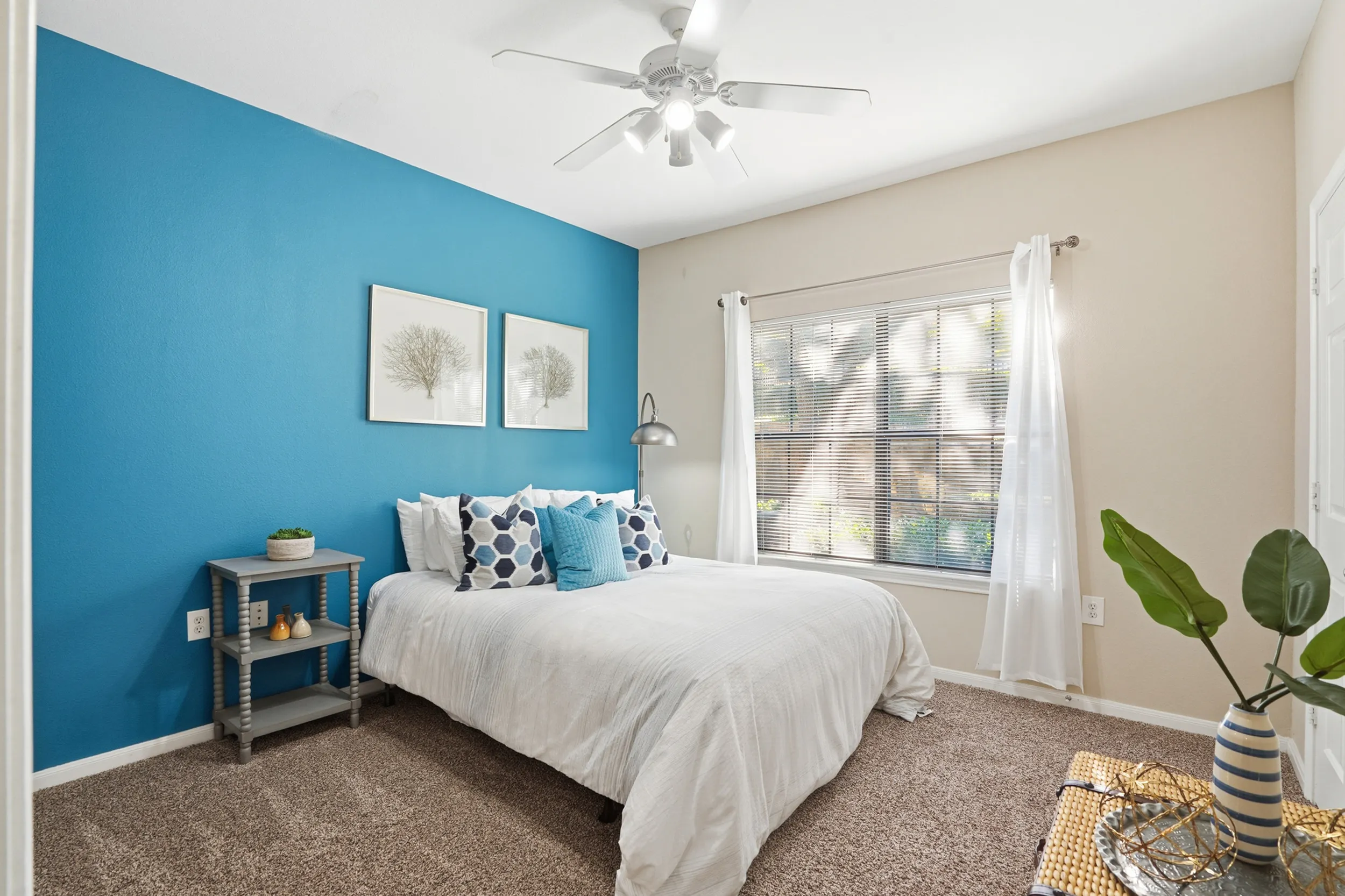 Inviting bedroom with elegant decor, featuring a cozy bed with a vibrant patterned duvet, large window for natural light, and stylish artwork.