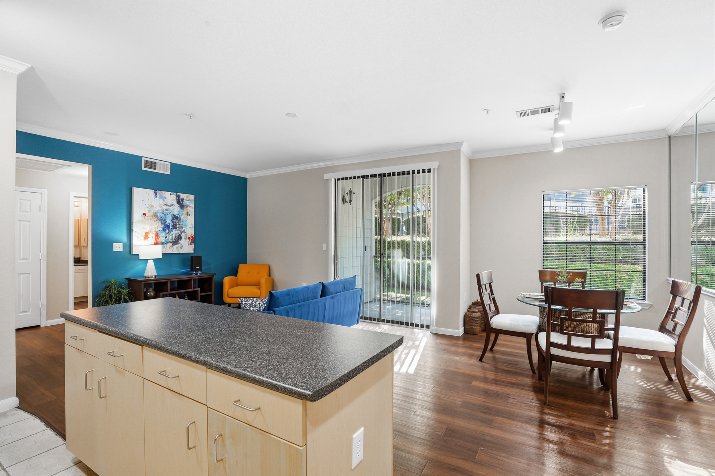 Elegant living and dining area with abundant natural light, featuring stylish furniture and a cozy dining setup perfect for entertaining.