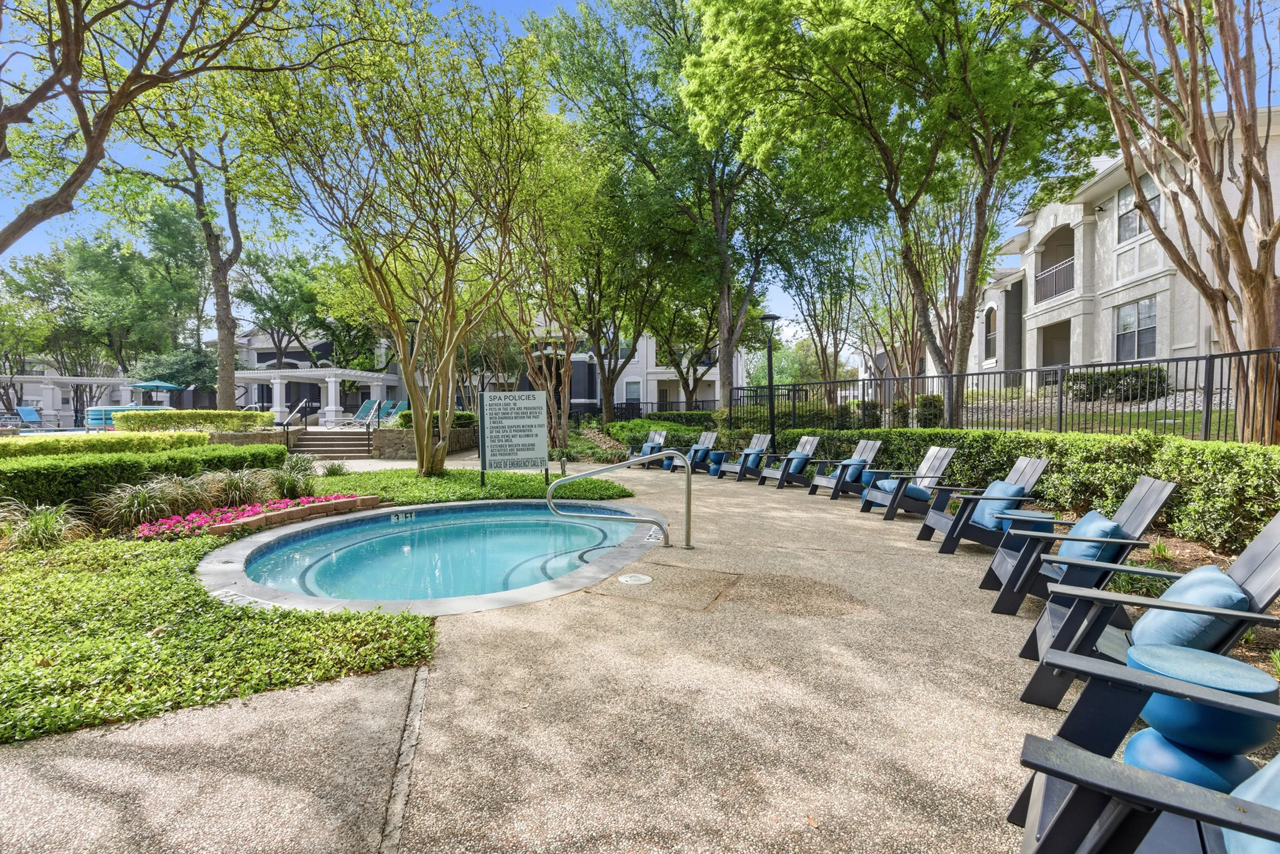 Beautiful apartment complex with lush greenery, a crystal-clear swimming pool, and a relaxing hot tub, perfect for serene outdoor living.