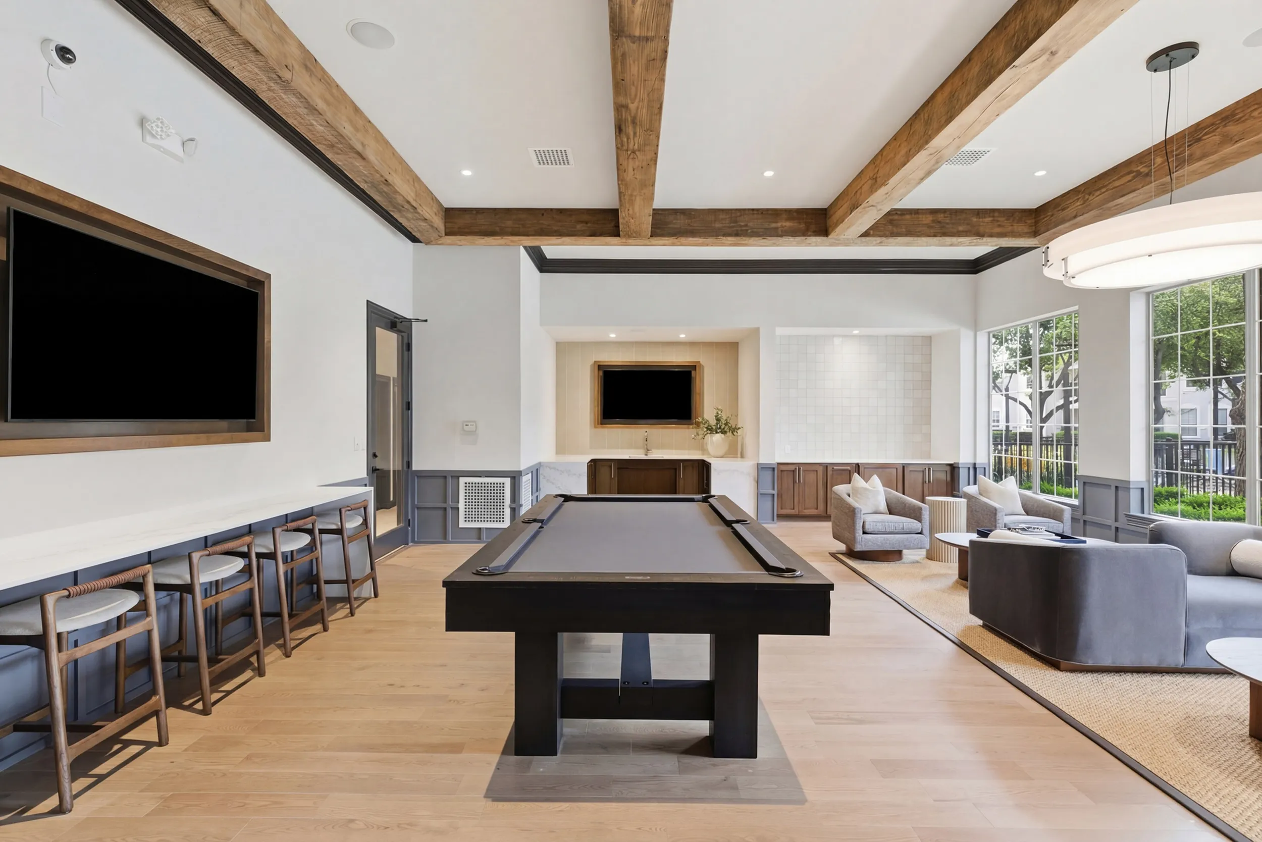 Elegant recreation room with a pool table, cozy seating, and modern kitchen, offering a perfect space for relaxation and entertainment.
