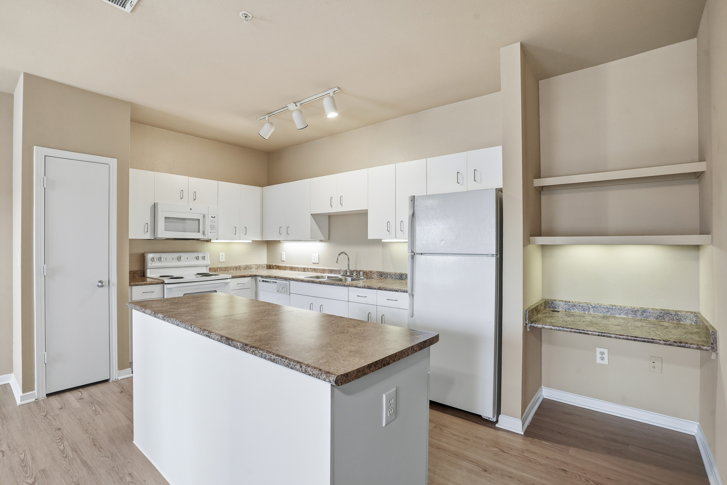 Large Kitchen with amble storage space, built in island, pantry, and built-in desk with shelving.