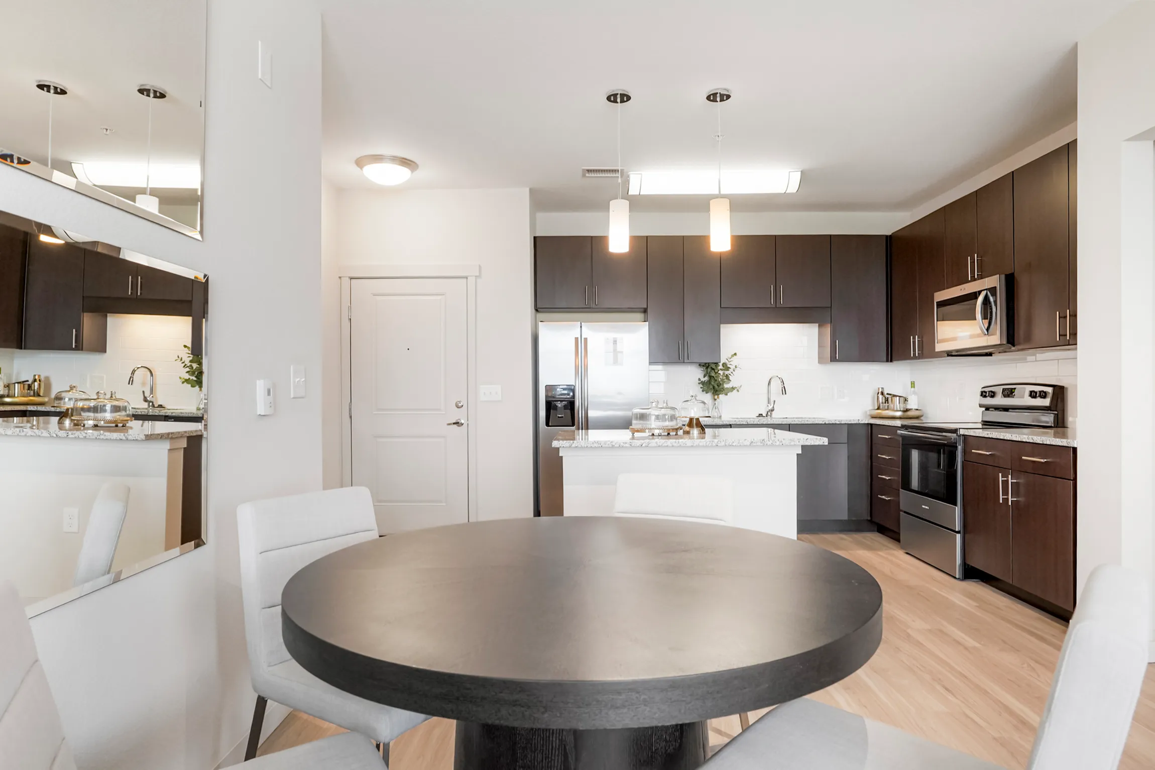 Modern kitchen with sleek dark cabinets, granite countertops, and stainless steel appliances, featuring a cozy breakfast bar with stylish stools.