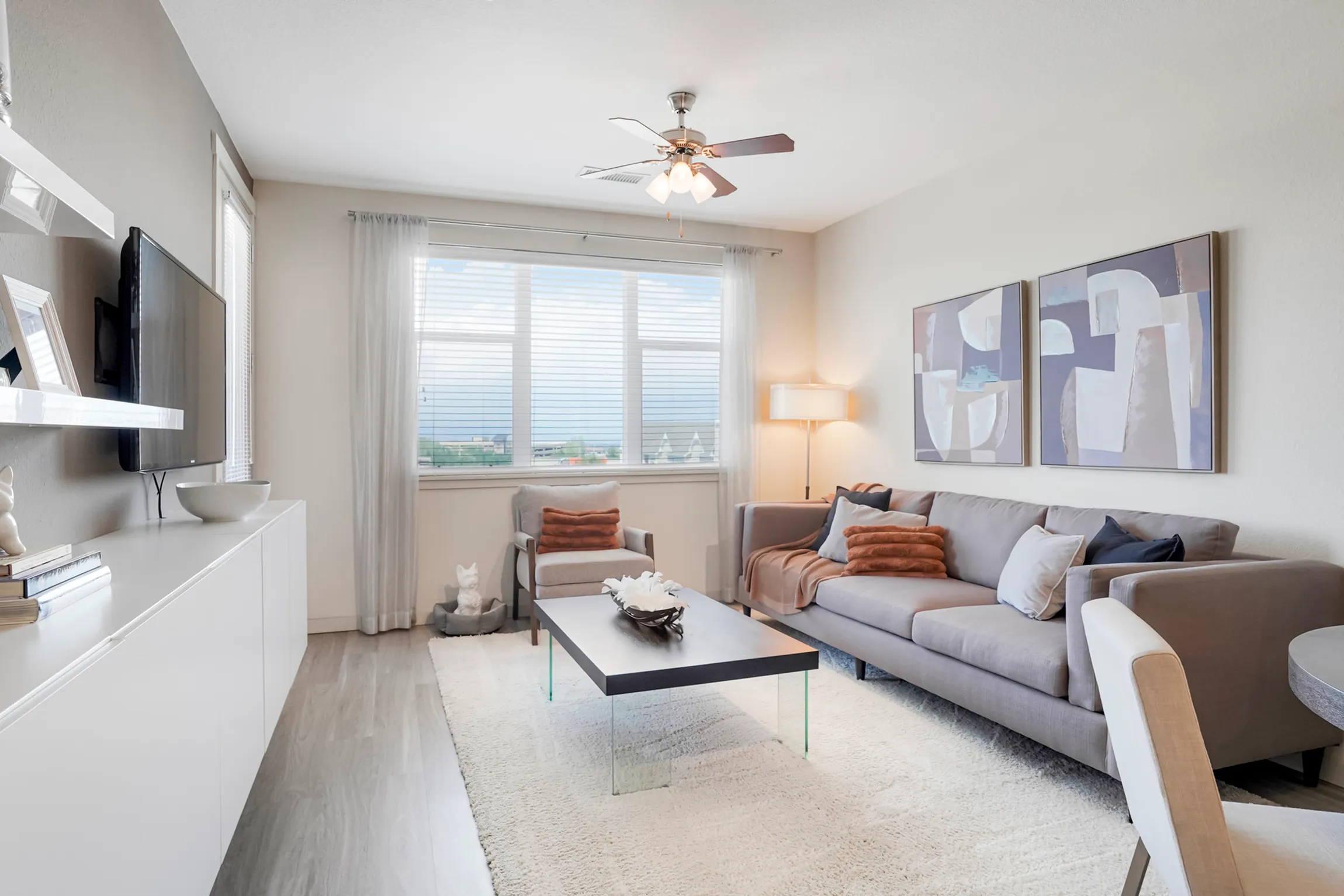 Elegant living area with contemporary decor, featuring a plush sofa, vibrant artwork, and an open concept kitchen with sleek cabinetry.