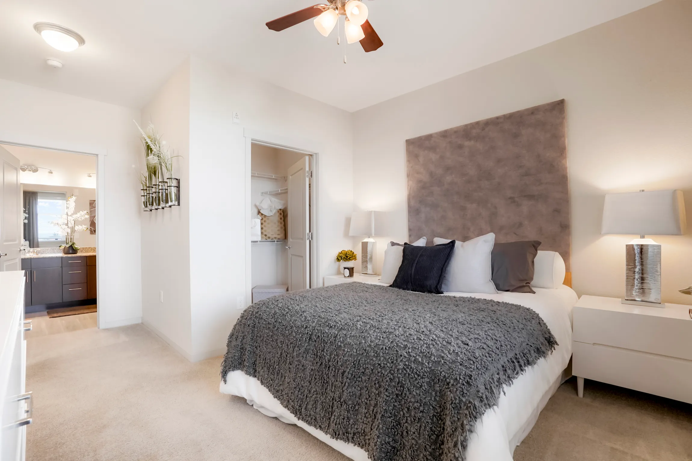 Inviting bedroom with elegant decor, modern art, and bright accents, featuring a cozy bed with colorful cushions and a stylish nightstand.