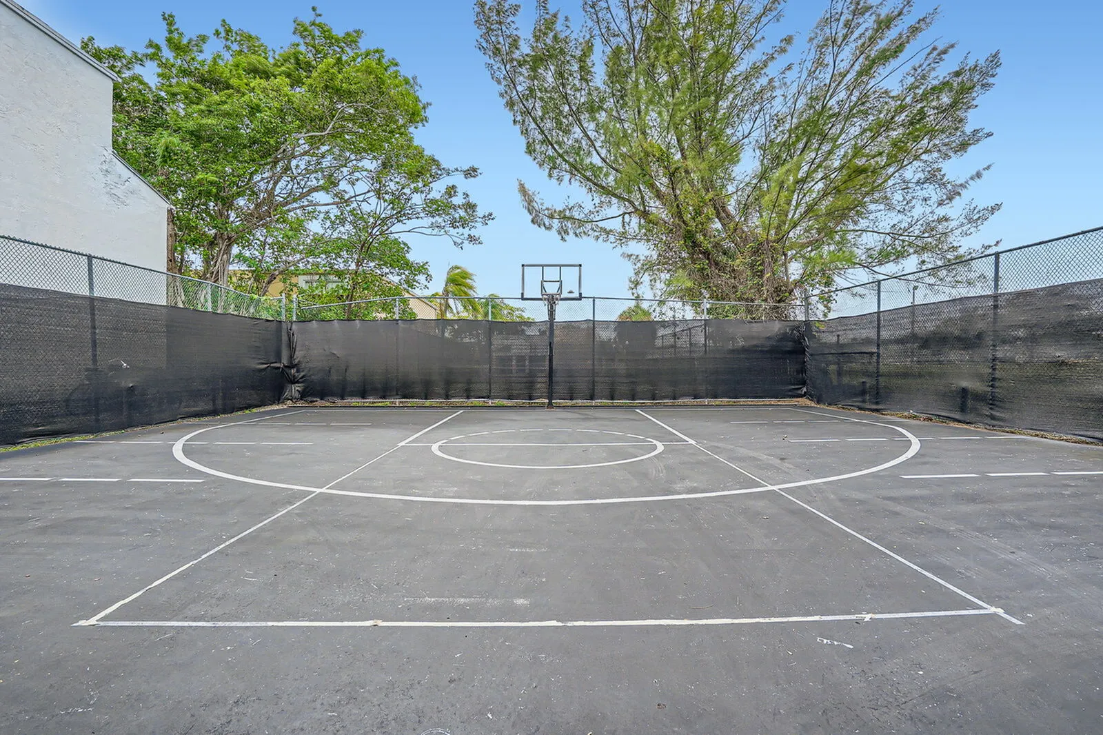 Inviting outdoor basketball court surrounded by lush trees, perfect for sports enthusiasts and leisurely activities.