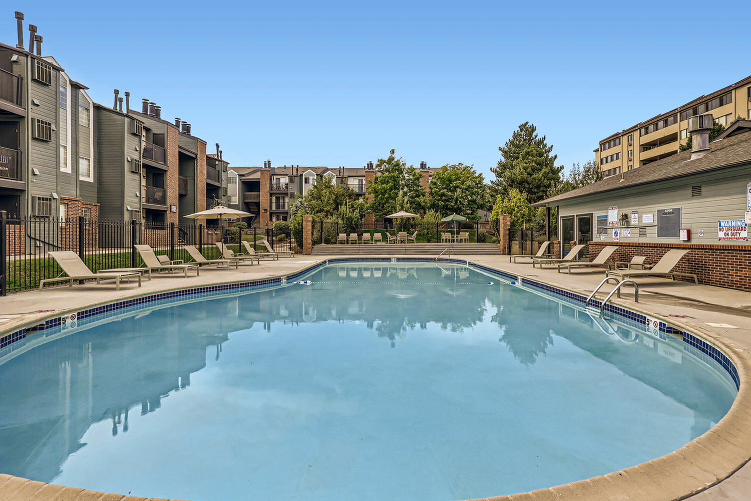 Inviting pool area surrounded by modern apartments with ample lounge chairs and greenery.