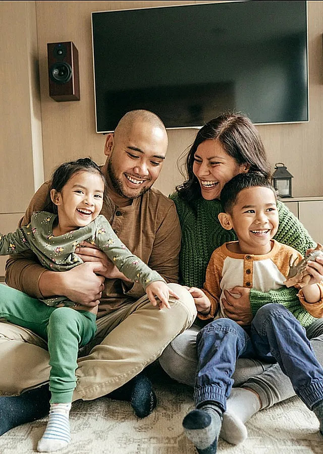 Happy family enjoying quality time in a modern, cozy living room with stylish decor and a large flat-screen TV.