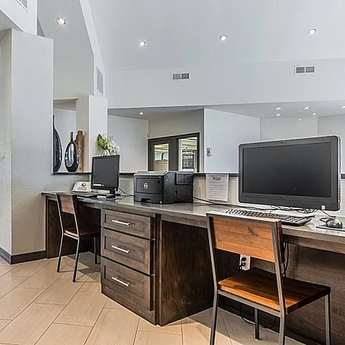 Sleek modern office space with stylish wooden furniture, dual computer workstations, and a bright, open layout.