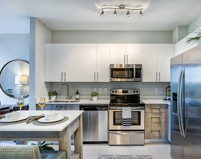 Modern open-concept living space with stylish decor, featuring a cozy seating area, elegant dining table, and sleek kitchen with stainless steel appliances.