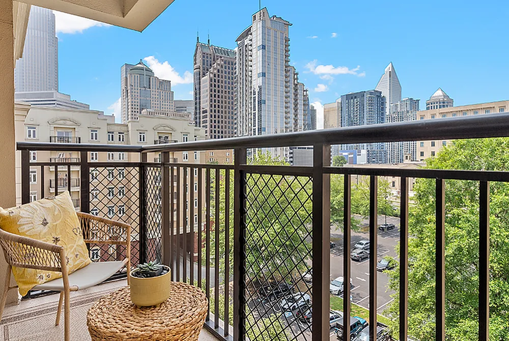 Charming balcony with cozy seating, offering stunning city skyline views and lush greenery.