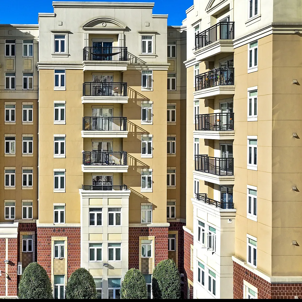 Elegant urban apartment building with stylish balconies and modern architecture, bathed in sunshine.