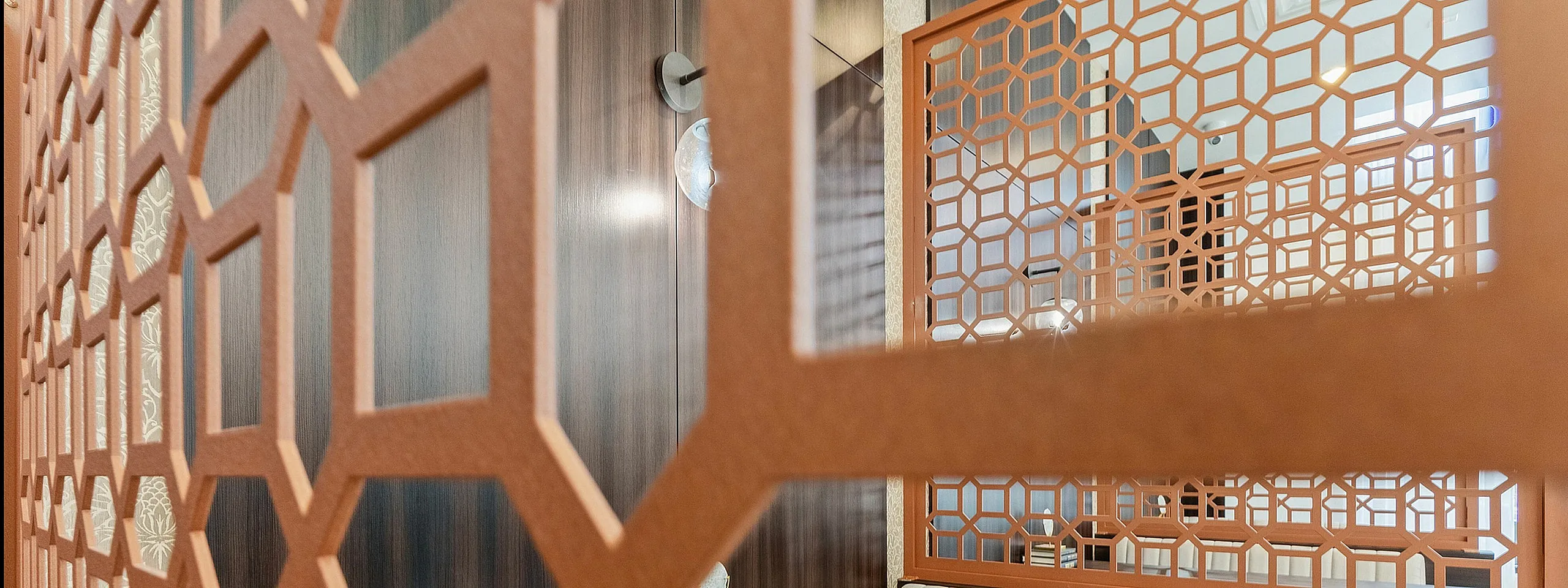 Elegant dining nook with patterned wood partition and cozy seating, perfect for intimate gatherings.