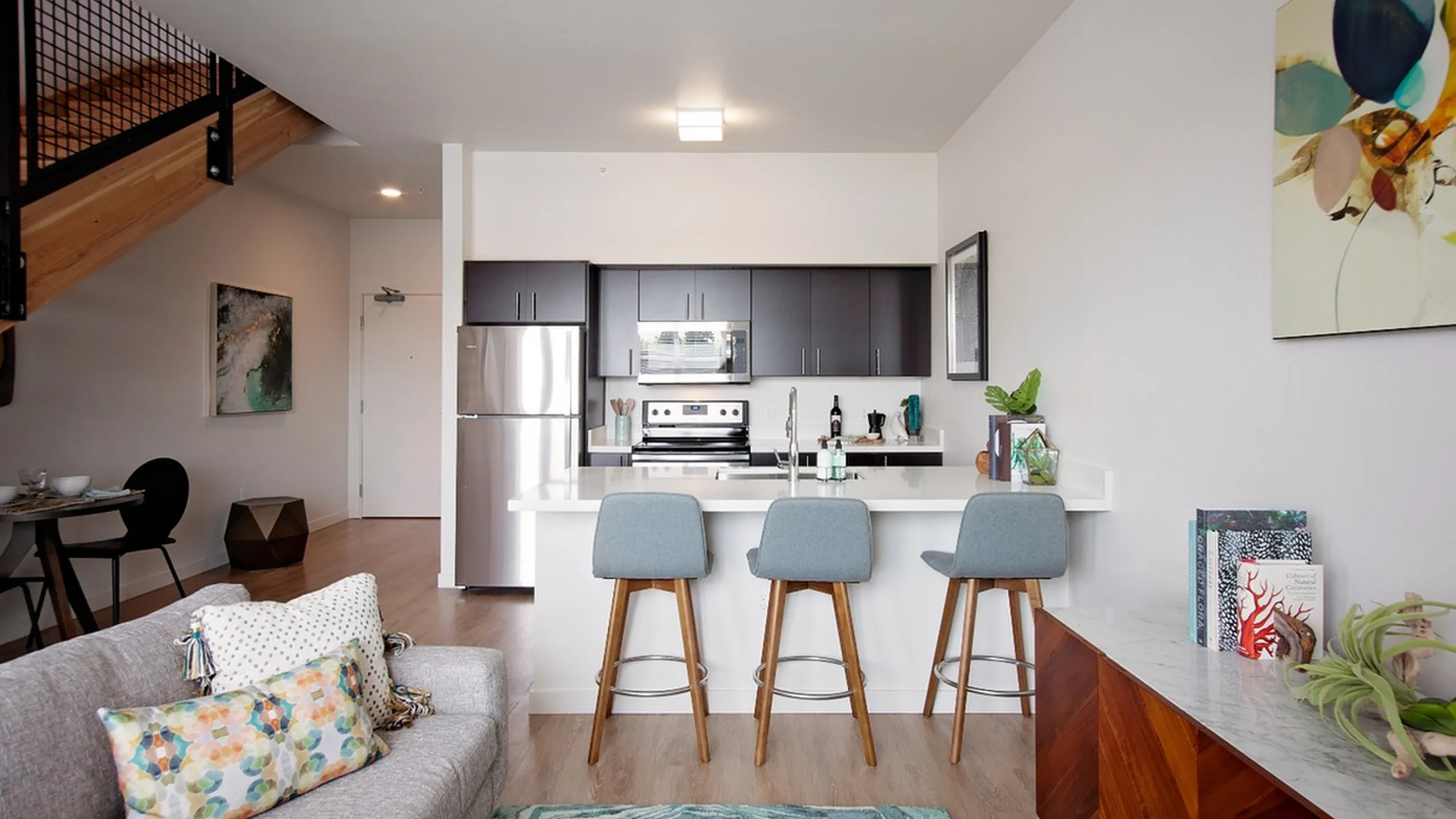 Modern apartment featuring a sleek kitchen with stainless steel appliances, elegant bar seating, and stylish decor, perfect for urban living.
