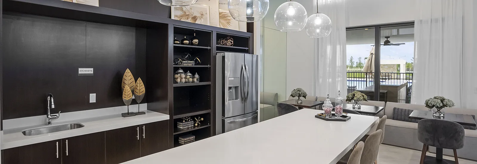 Luxurious open-plan kitchen with modern appliances, elegant lighting, and a sleek dining area overlooking a spacious balcony.