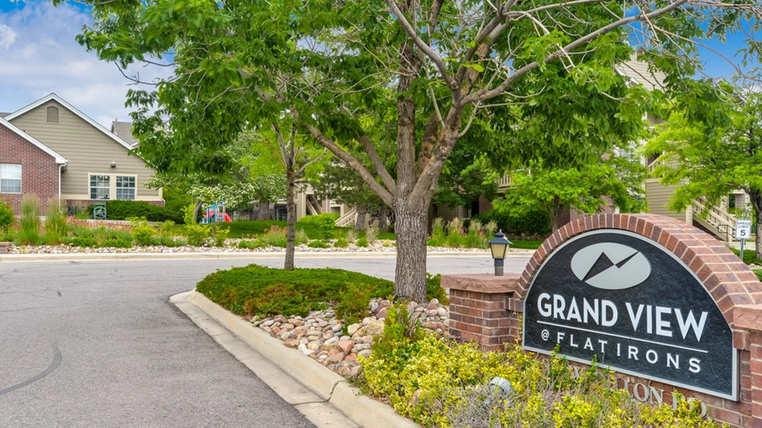 Charming entrance to Grand View at Flatirons, featuring lush landscaping and inviting community vibe.