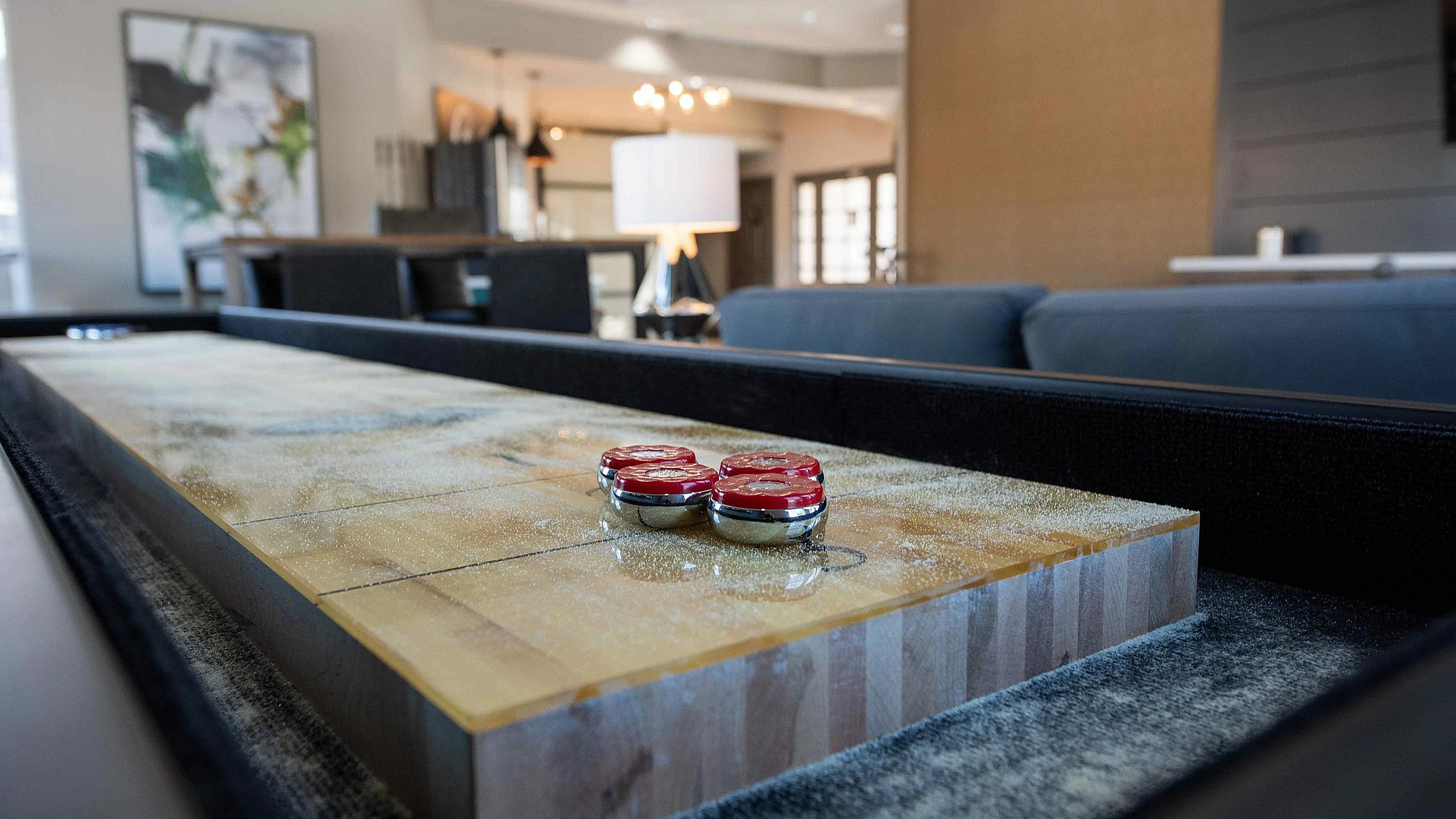Modern living area with a stylish shuffleboard table, chic decor, and ambient lighting.