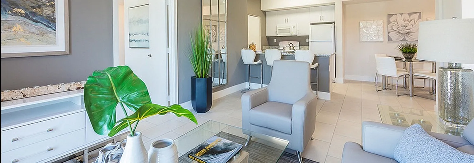 Bright and modern open-concept living room with stylish decor, comfortable seating, and a sleek kitchen with bar stools.