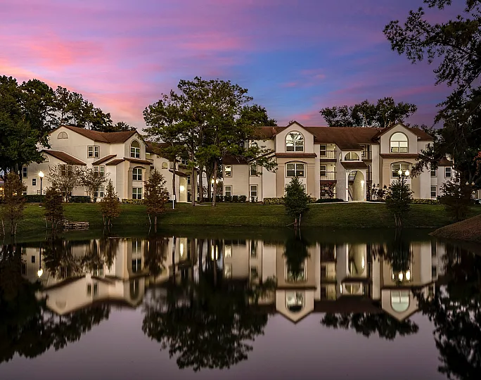 Cozy lit apartments buildings amongst lush trees at sunset