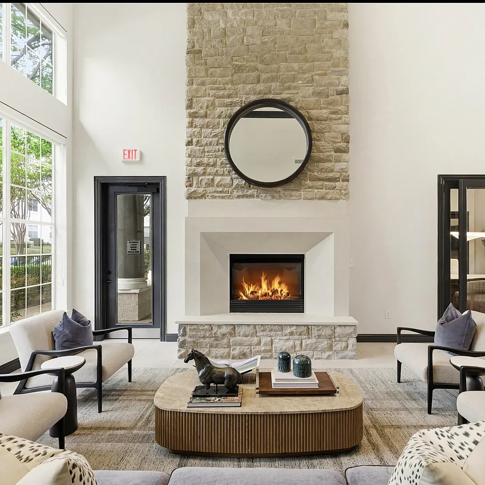 Luxurious apartment lobby featuring high ceilings, large windows, elegant chandeliers, a stone fireplace, and modern decor.