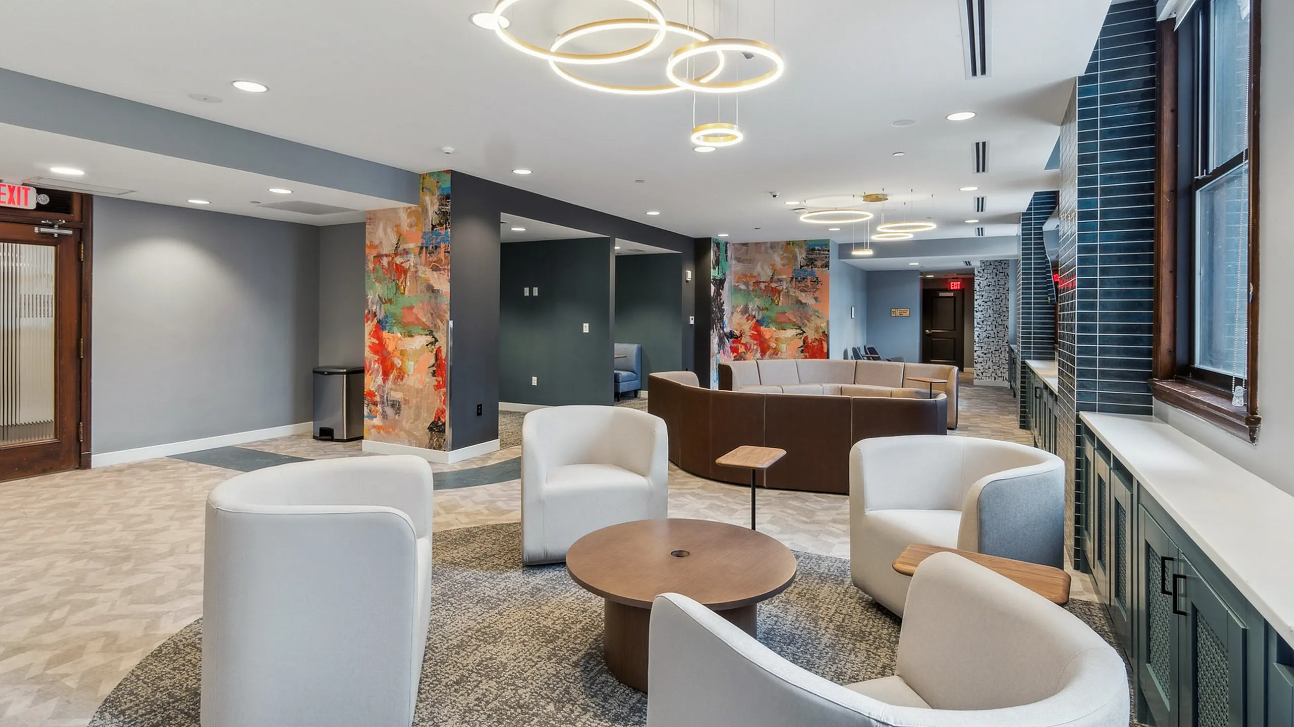Modern lounge area with chic circular lighting, comfortable seating, and vibrant artwork on walls, exuding contemporary elegance.