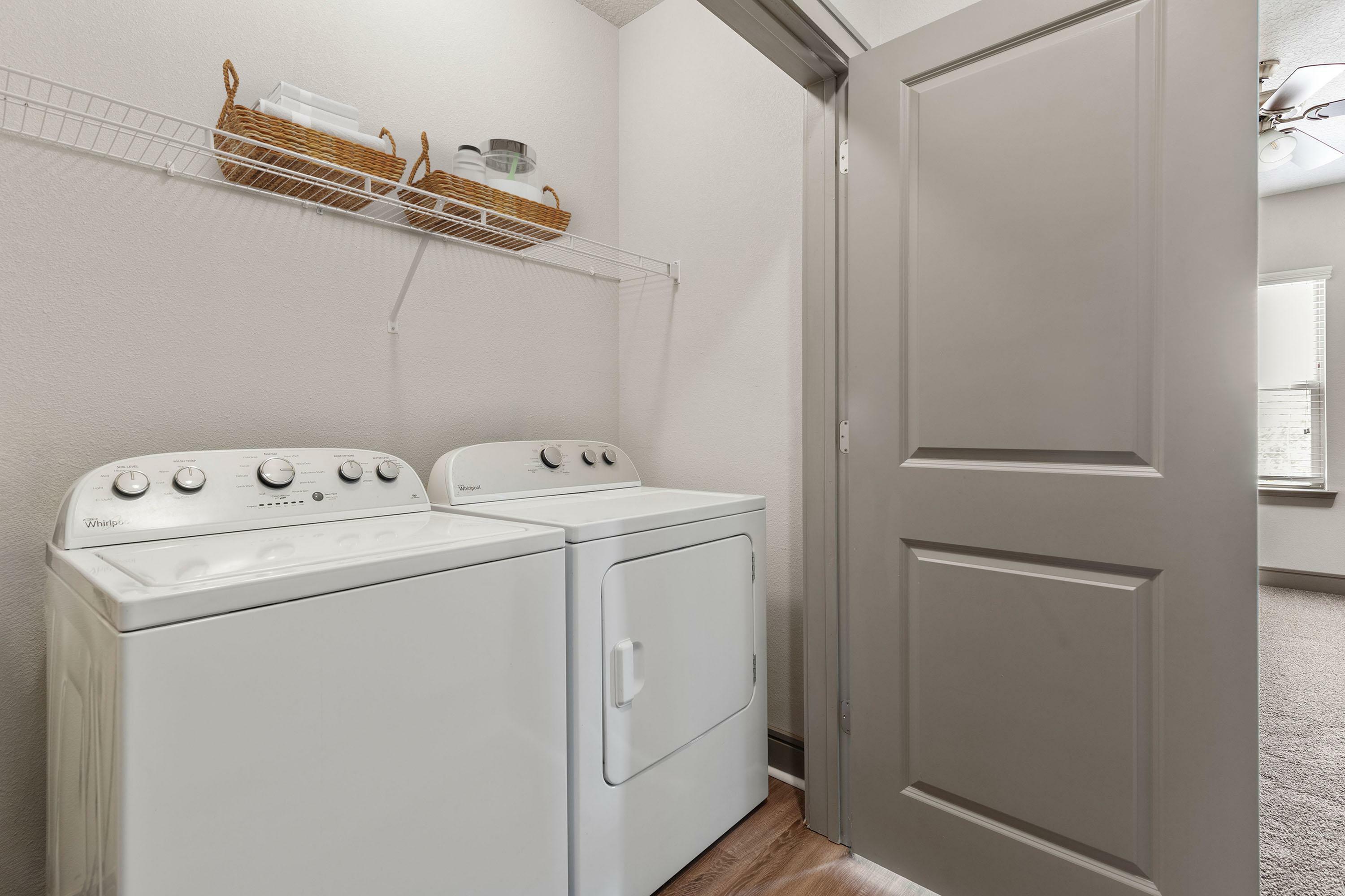 Modern laundry room with efficient washer and dryer set, accented by sleek shelving for organized storage.