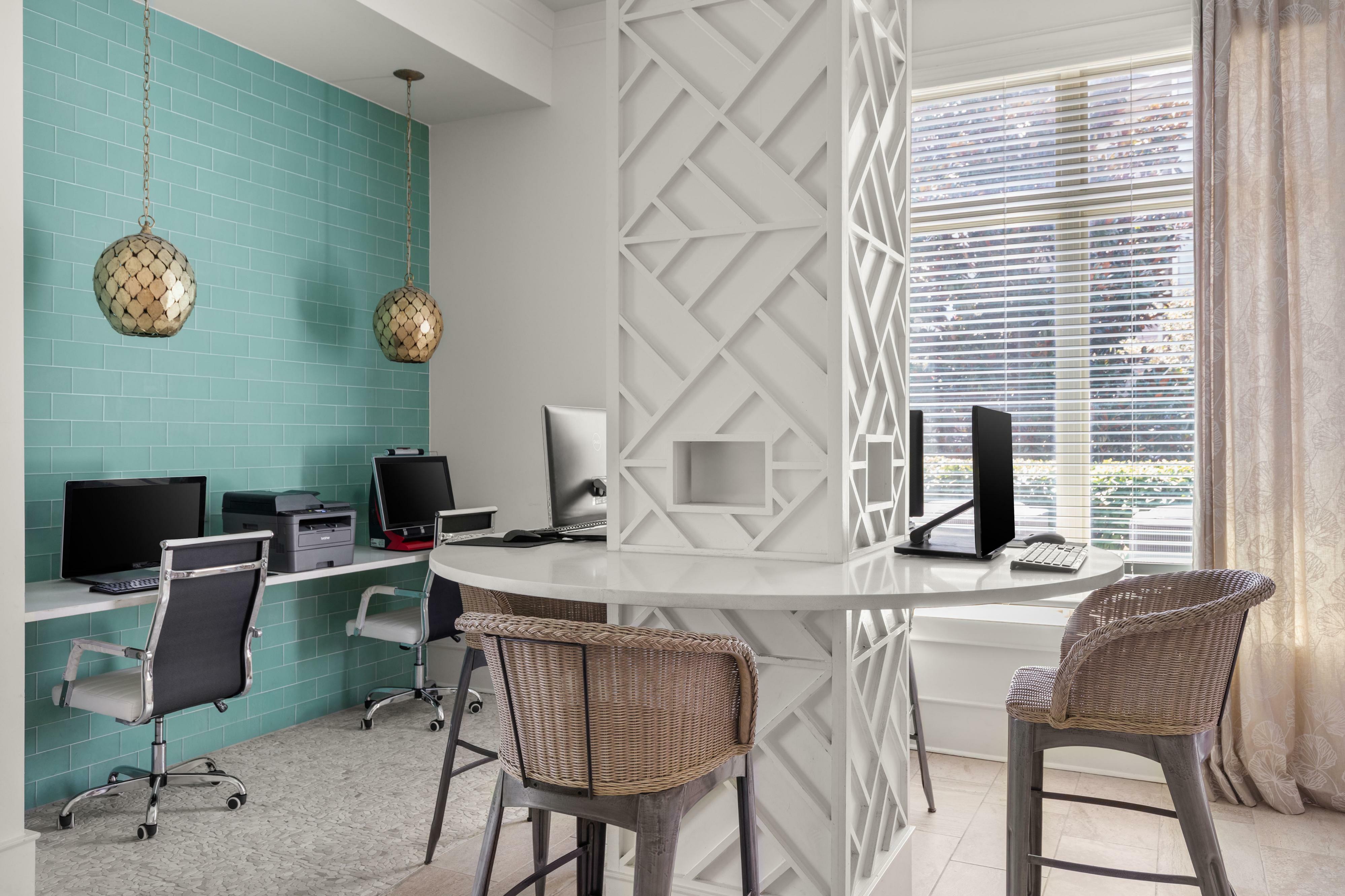 Chic workspace featuring a stylish mosaic aqua-tiled wall, two modern computer stations, and elegant pendant lighting, perfect for productivity and creativity.