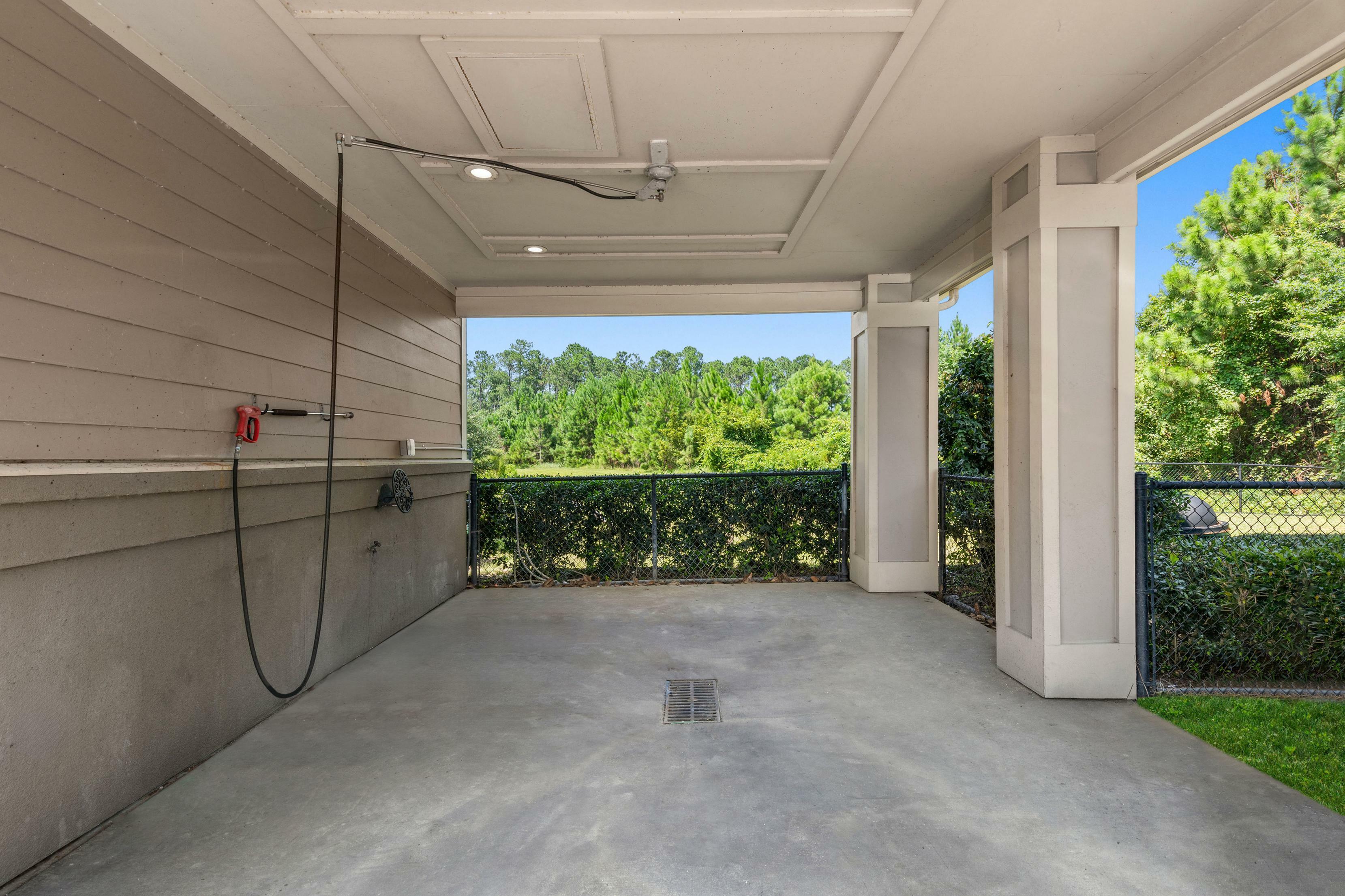 Inviting carport with a sleek design, offering a beautiful view of lush greenery in a serene neighborhood.