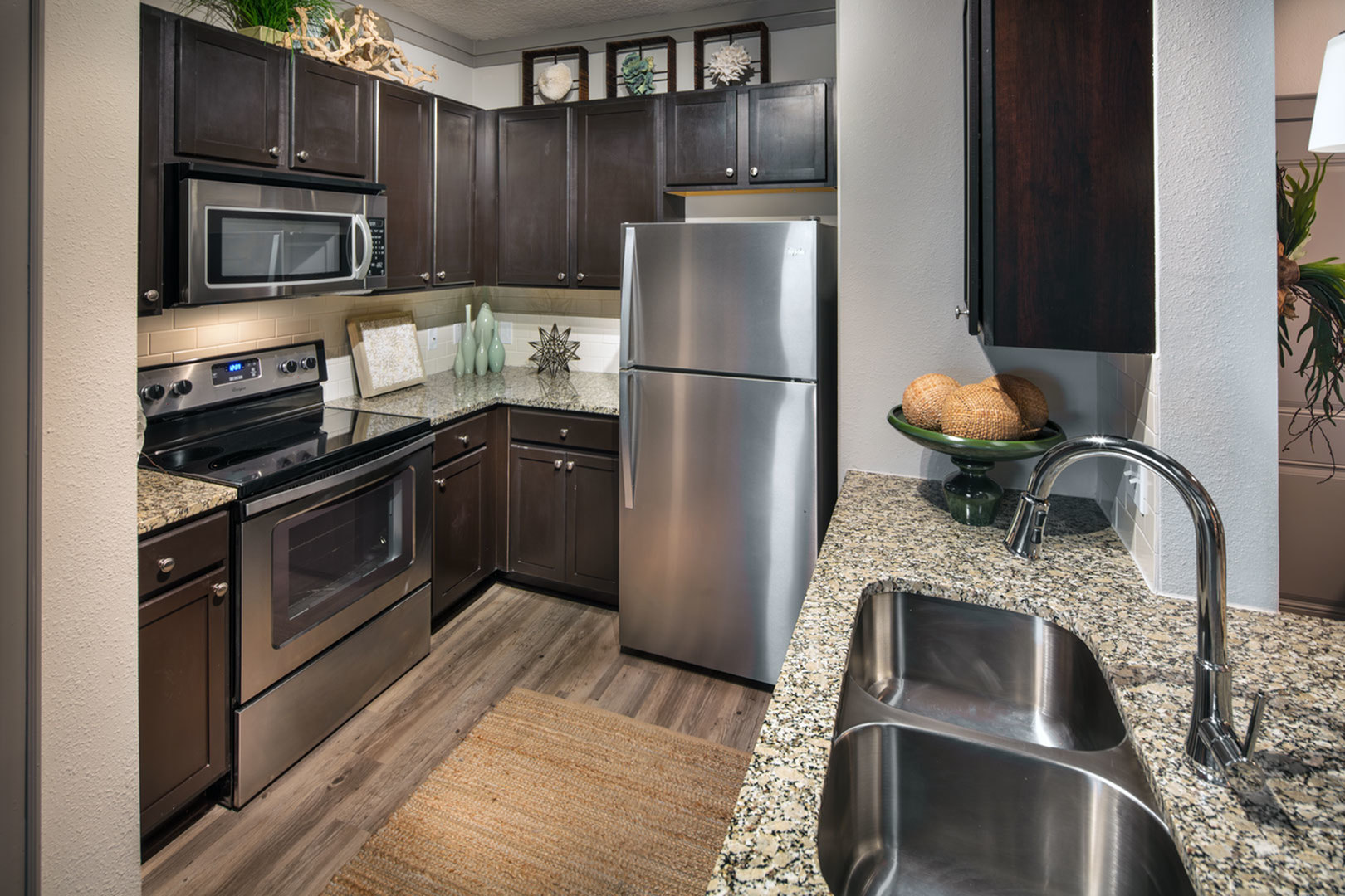 Modern kitchen with sleek stainless steel appliances, dark wood cabinetry, and elegant granite countertops.