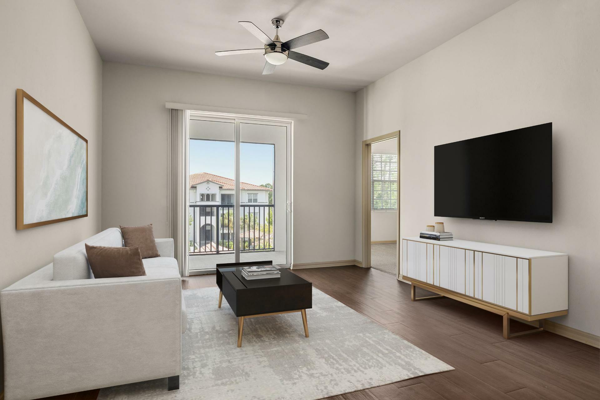 Modern living room with plush sofa, sleek TV setup, and balcony access, offering serene views and abundant natural light.