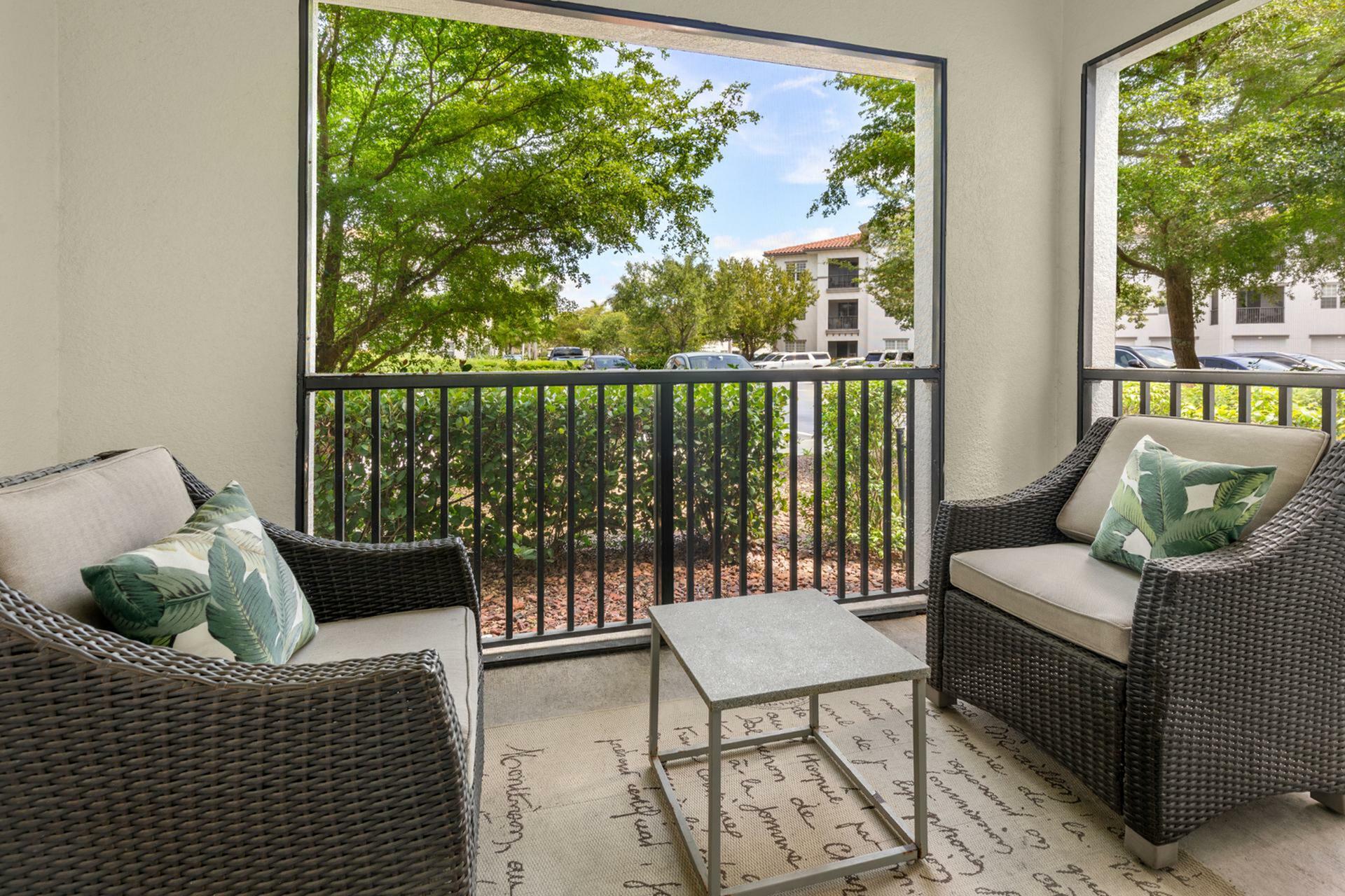 Charming patio view with cozy wicker chairs, surrounded by lush greenery and vibrant outdoor scenery.