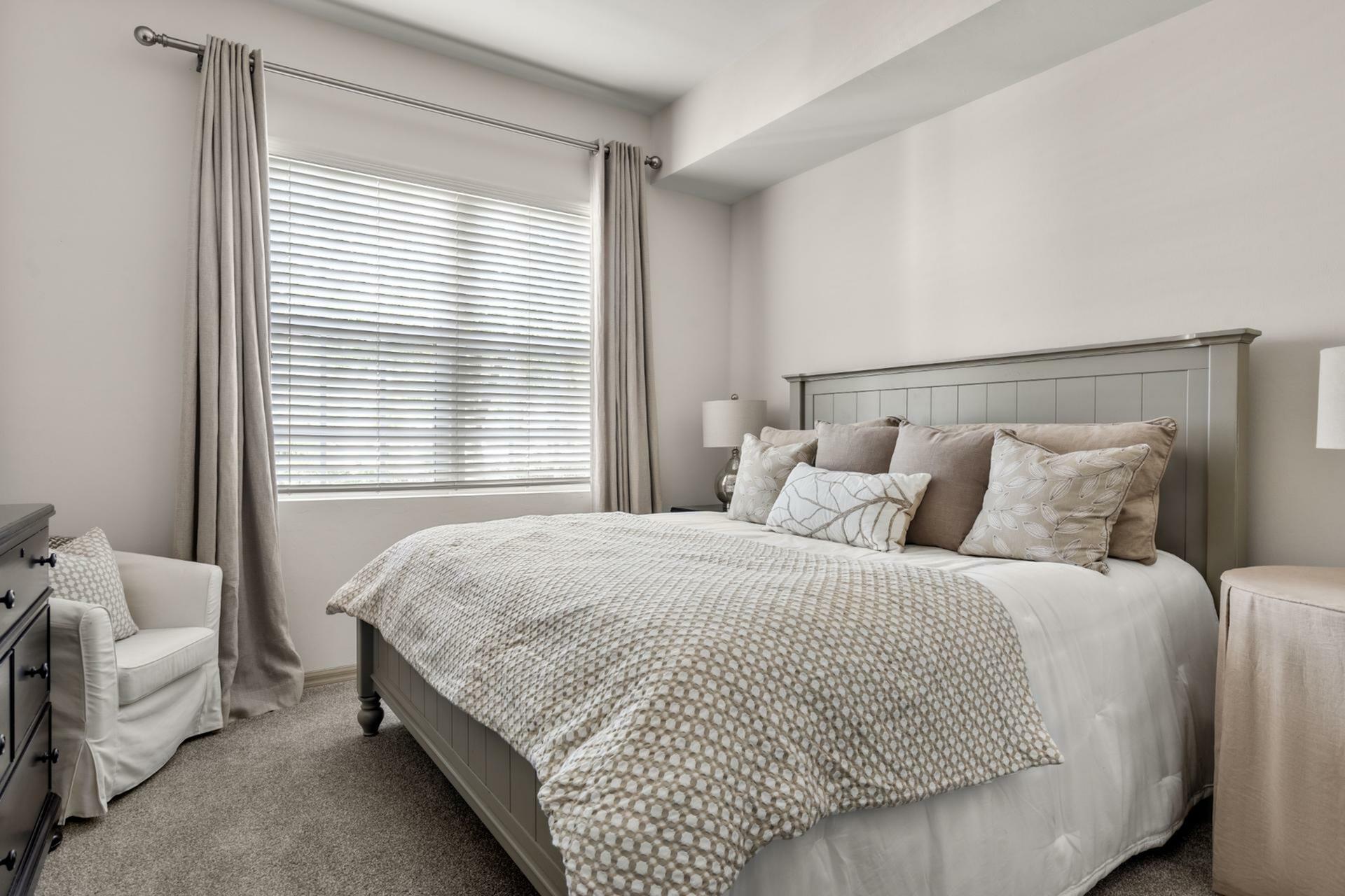 Elegantly designed bedroom with a plush bed, soft neutral tones, and ample natural light creating a cozy and inviting atmosphere.