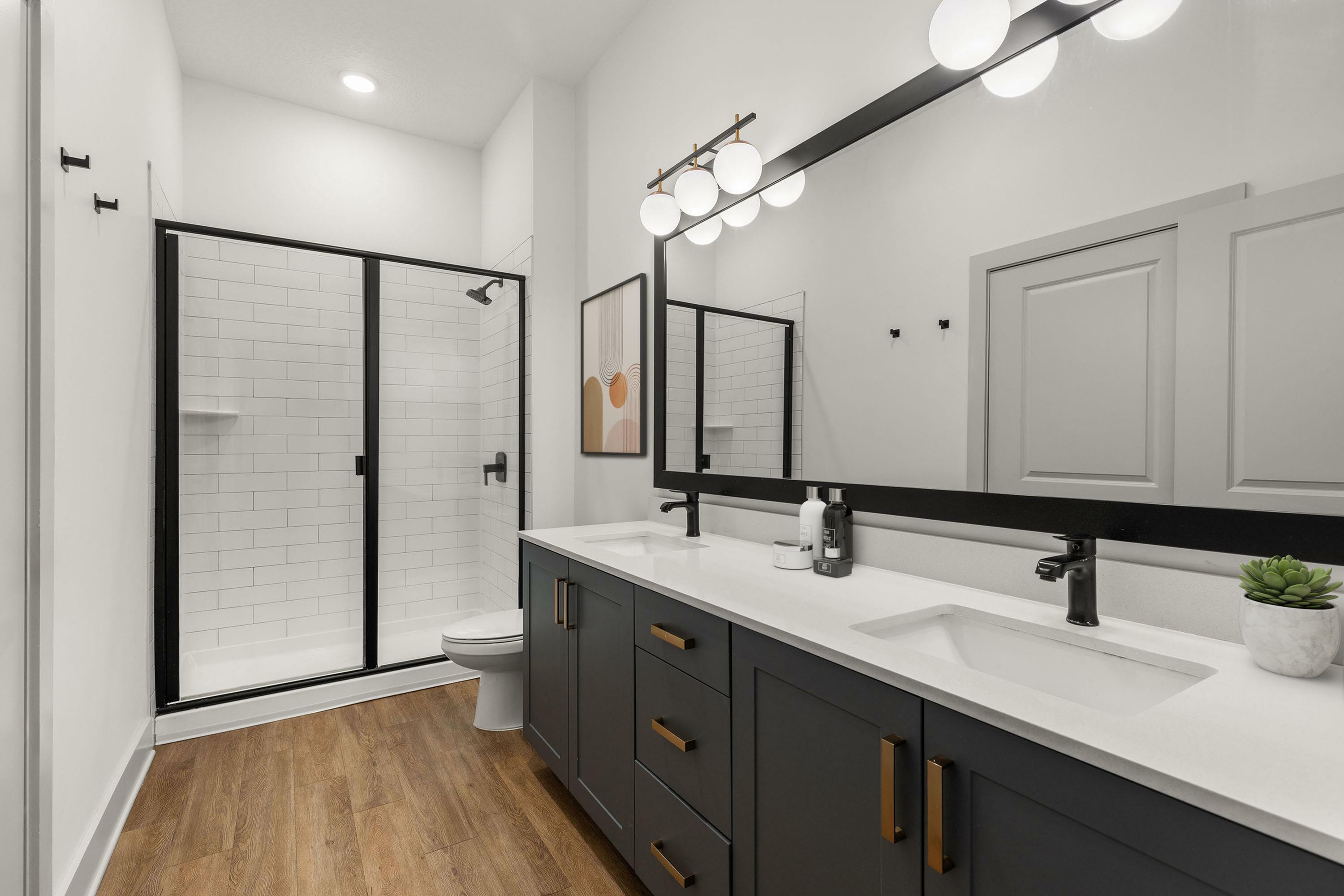 Elegant bathroom with a modern dual-sink vanity, large mirror, and a sleek glass-enclosed shower.