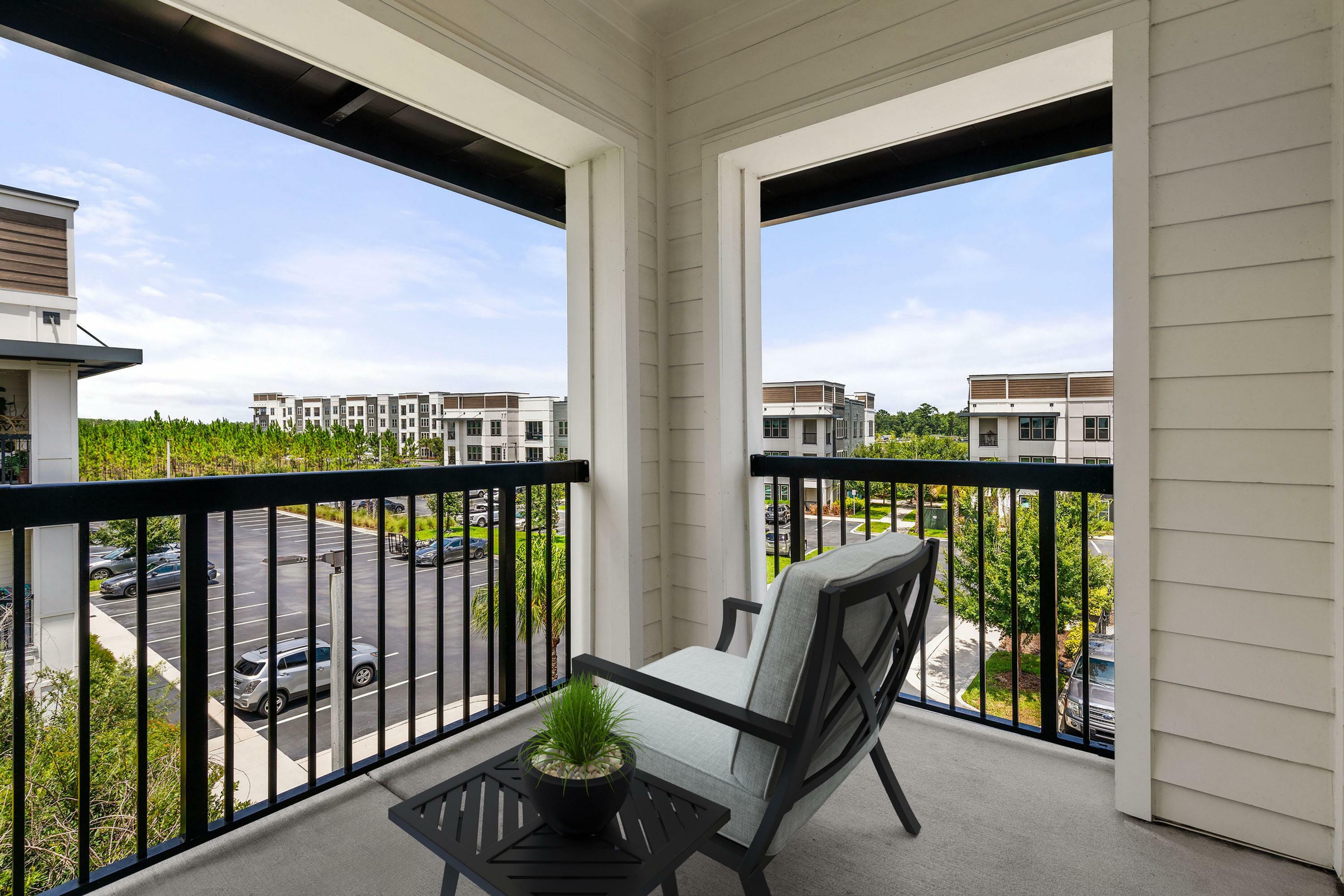 Charming balcony view showcasing lush greenery and modern apartment buildings, complete with comfortable outdoor seating.
