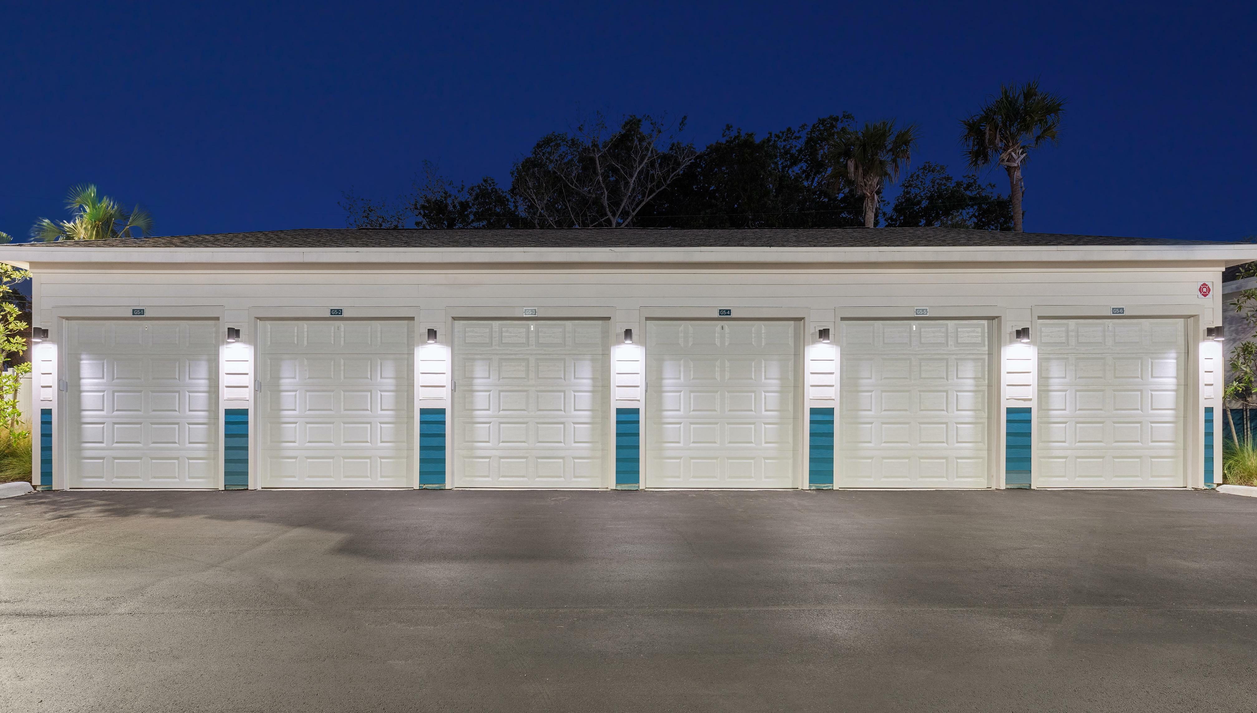 Elegant row of well-lit parking garages with modern design and palm tree surroundings, creating a serene atmosphere.